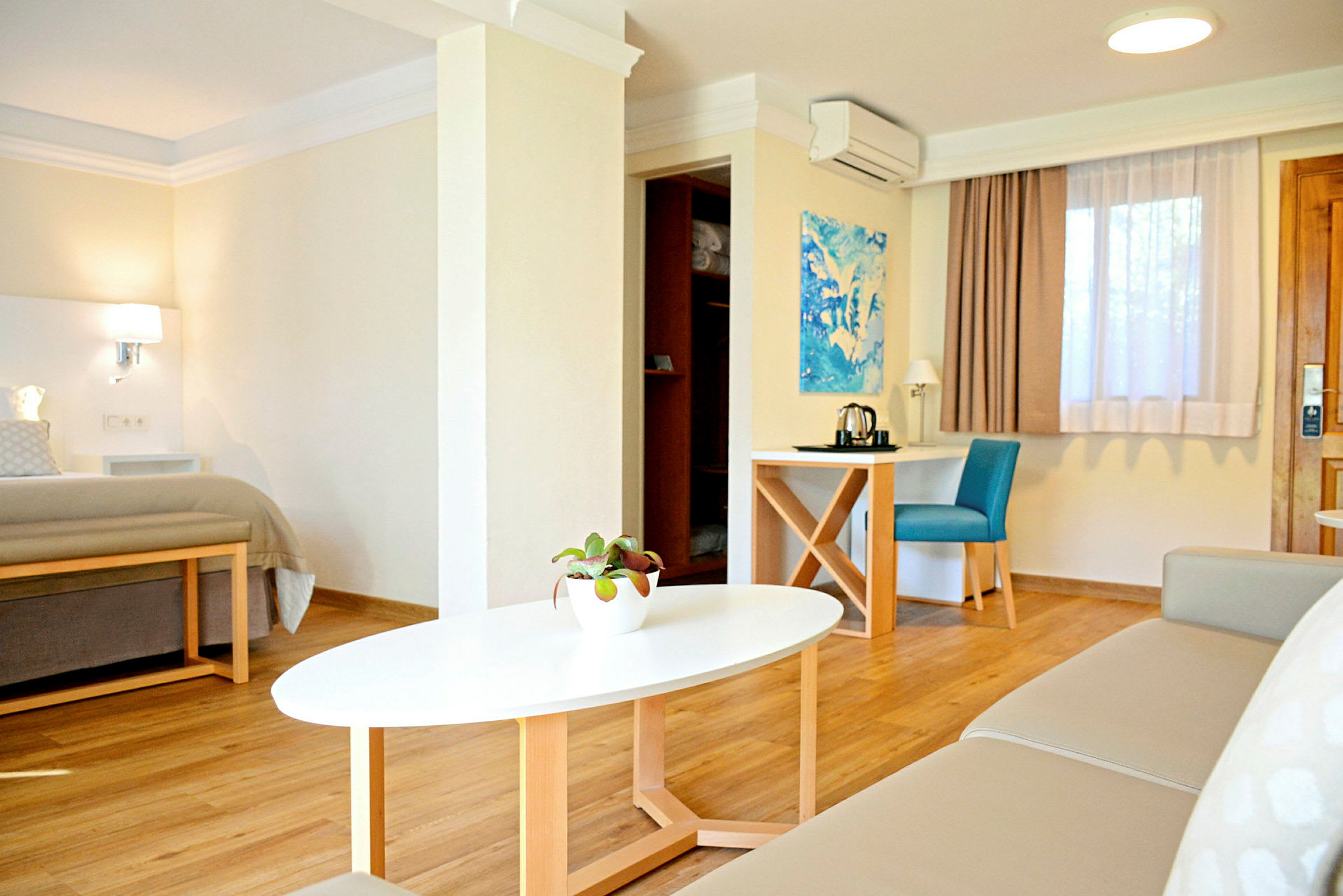 Ett modernt och ljust hotellrum med en säng, en soffa, ett soffbord och ett skrivbord med en stol. (AI-genererad text)