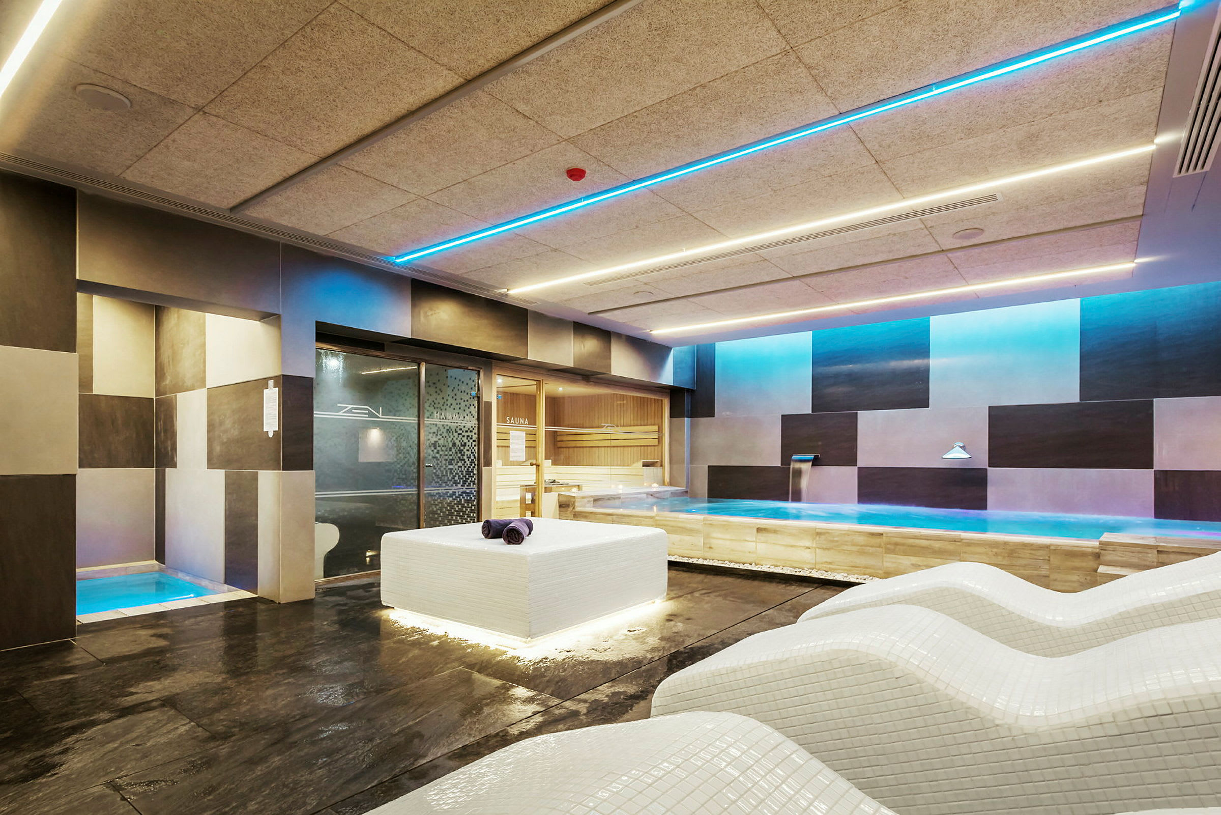 En modern spa-lokal med liggstolar och en jacuzzi, omgiven av en elegant inredning. (AI-genererad text)