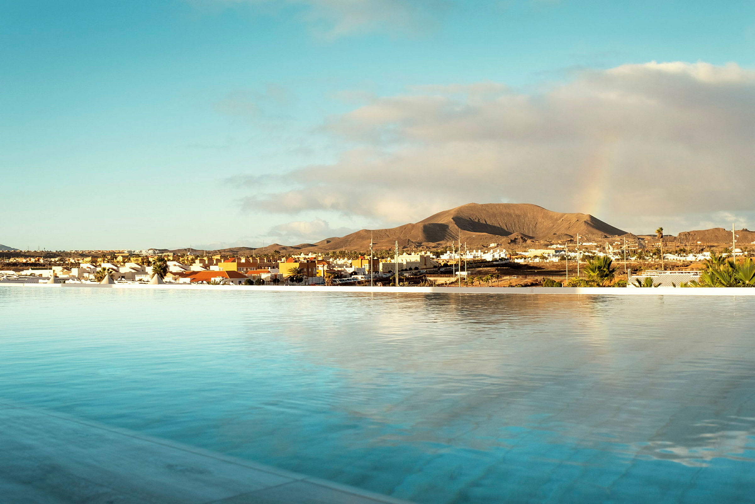 En vy över en panoramisk pool med en stad och ett berg i bakgrunden. (AI-genererad text)