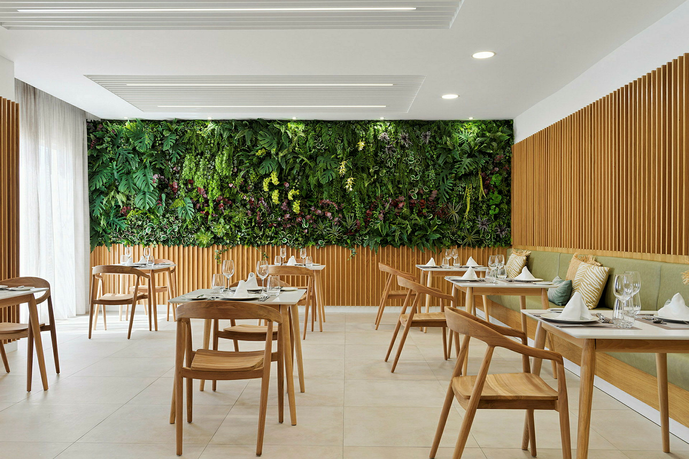 En modern restaurang med träbord och stolar, samt en grön vägg med växter. (AI-genererad text)