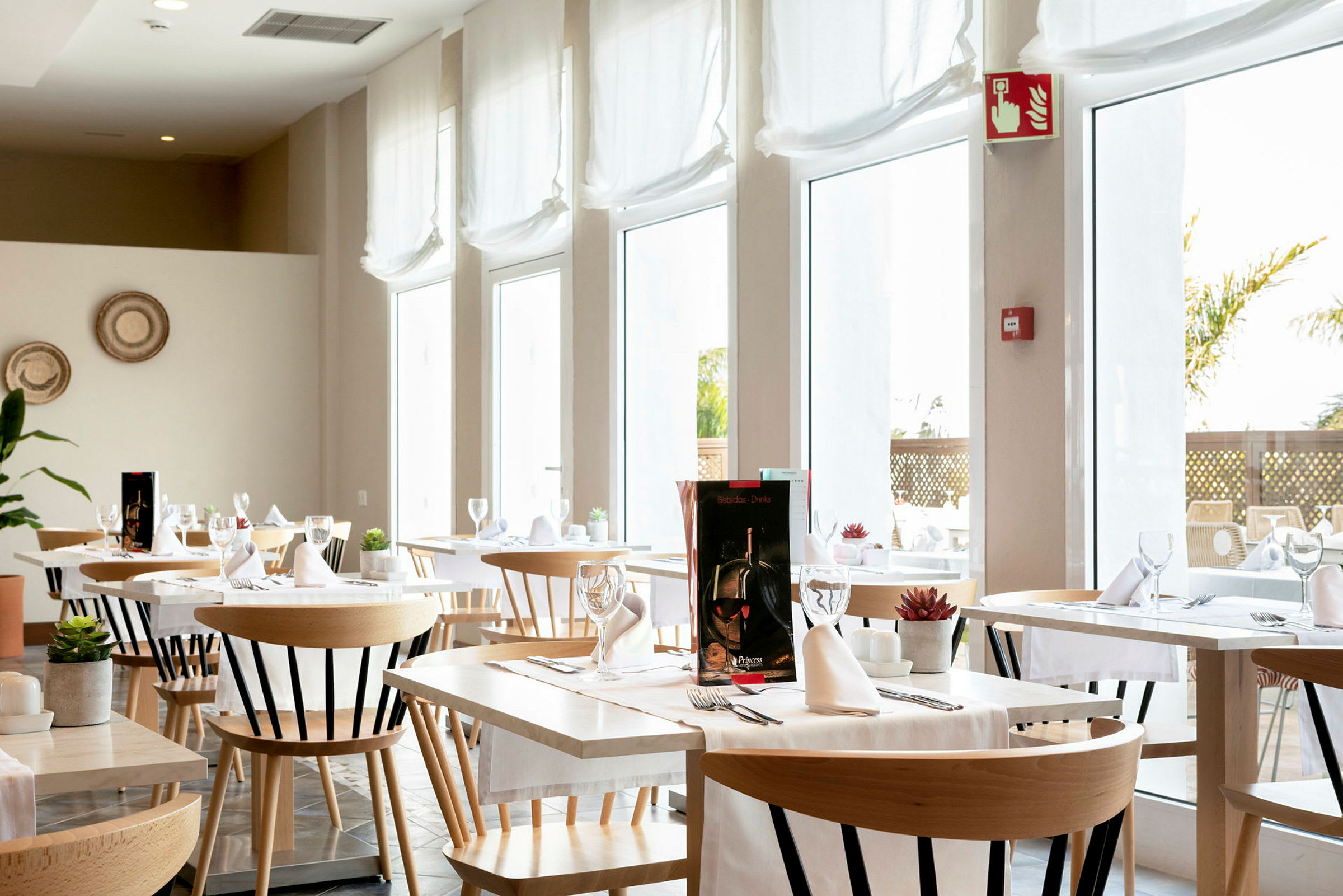 En ljus och modern restaurang med bord och stolar, inredd med vita bordsdukar och glas. (AI-genererad text)