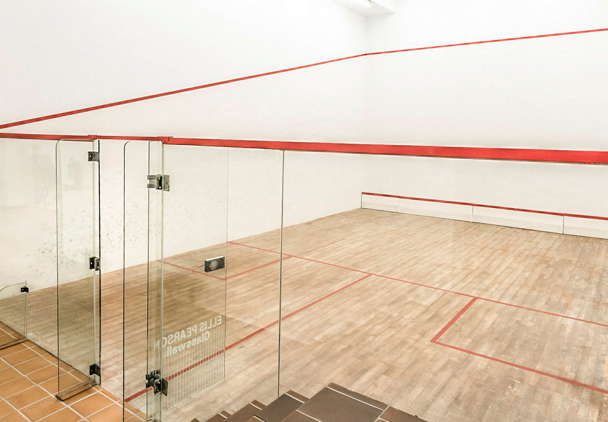 En squashplan med trägolv och glasväggar. (AI-genererad text)