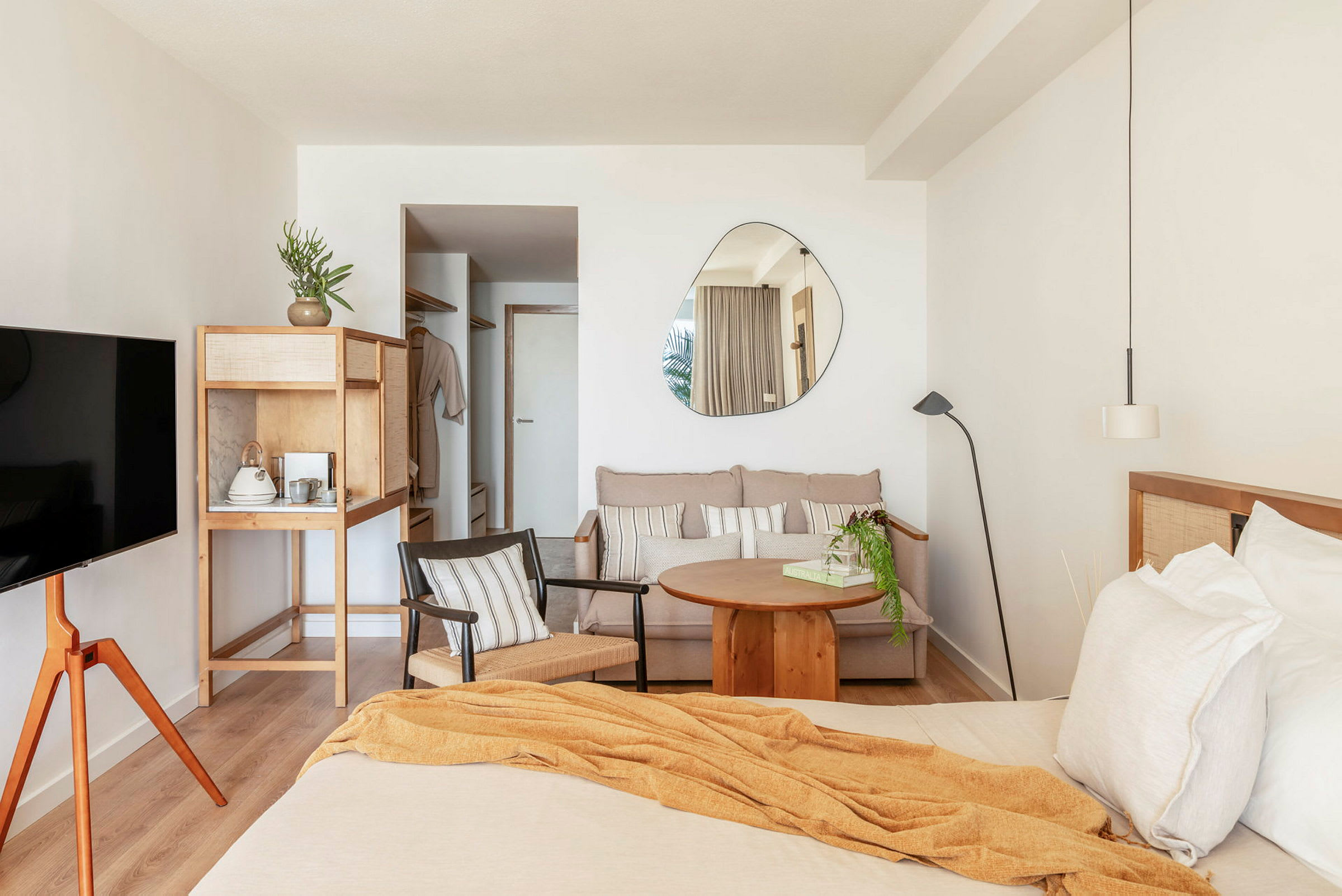 Ett hotellrum med en säng, en liten sittgrupp, en hylla med kaffekokare och en väggmonterad TV. (AI-genererad text)