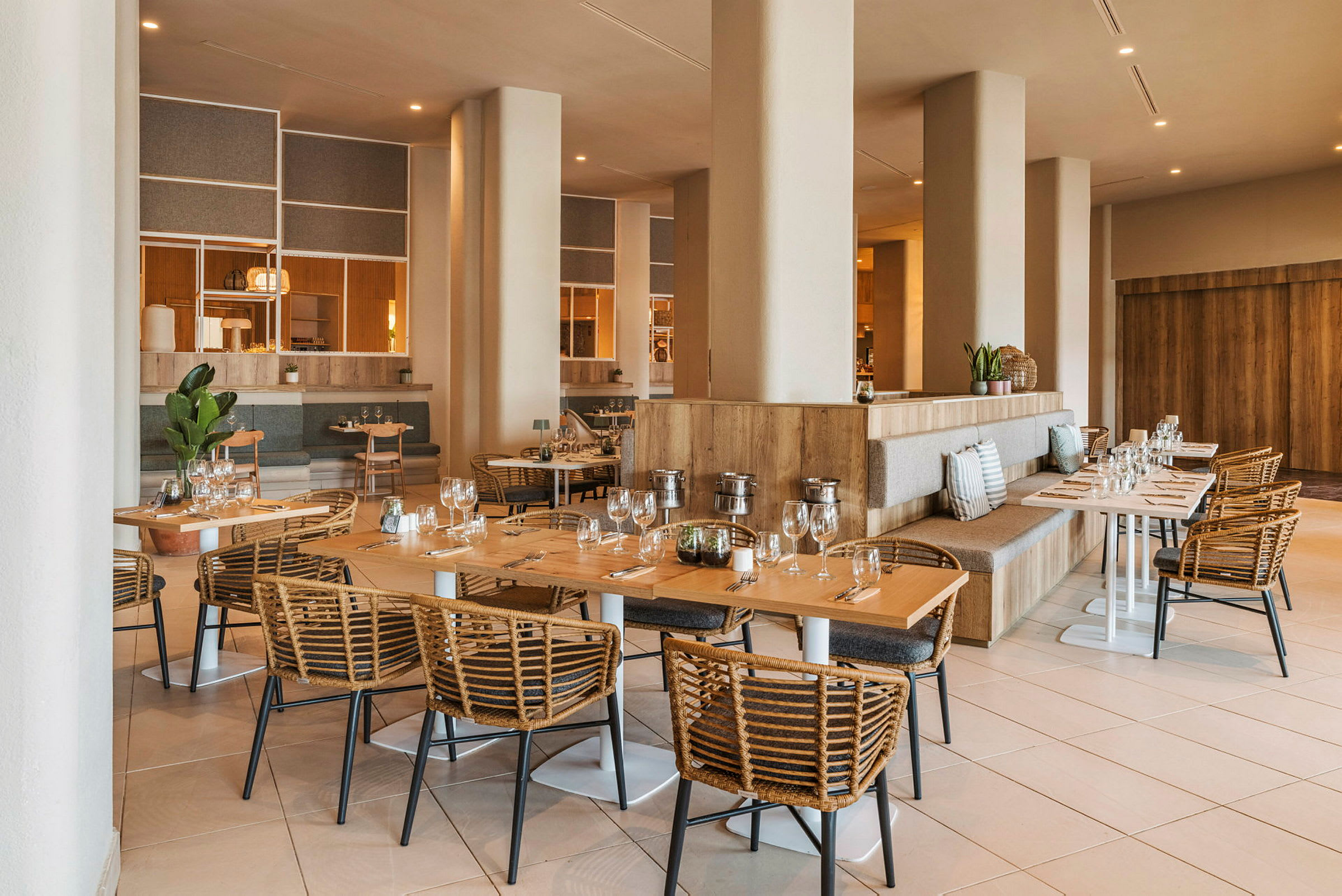 En rymlig och elegant inredd restaurang med träbord och flätade stolar. (AI-genererad text)