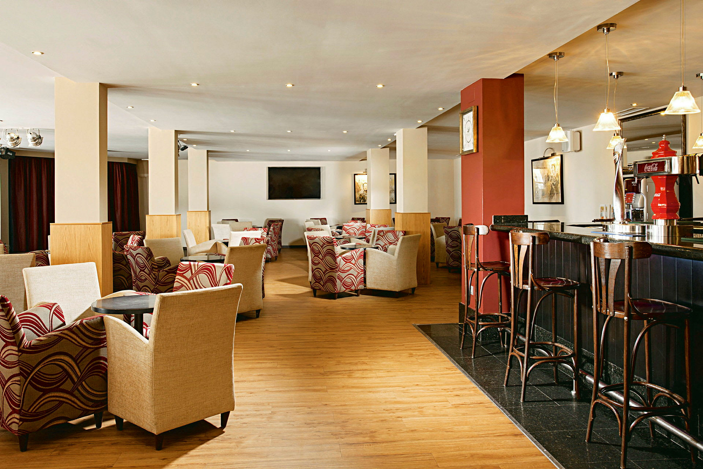 En hotellounge med fåtöljer och bord, barstolar vid en bardisk, och dekorativ inredning. (AI-genererad text)