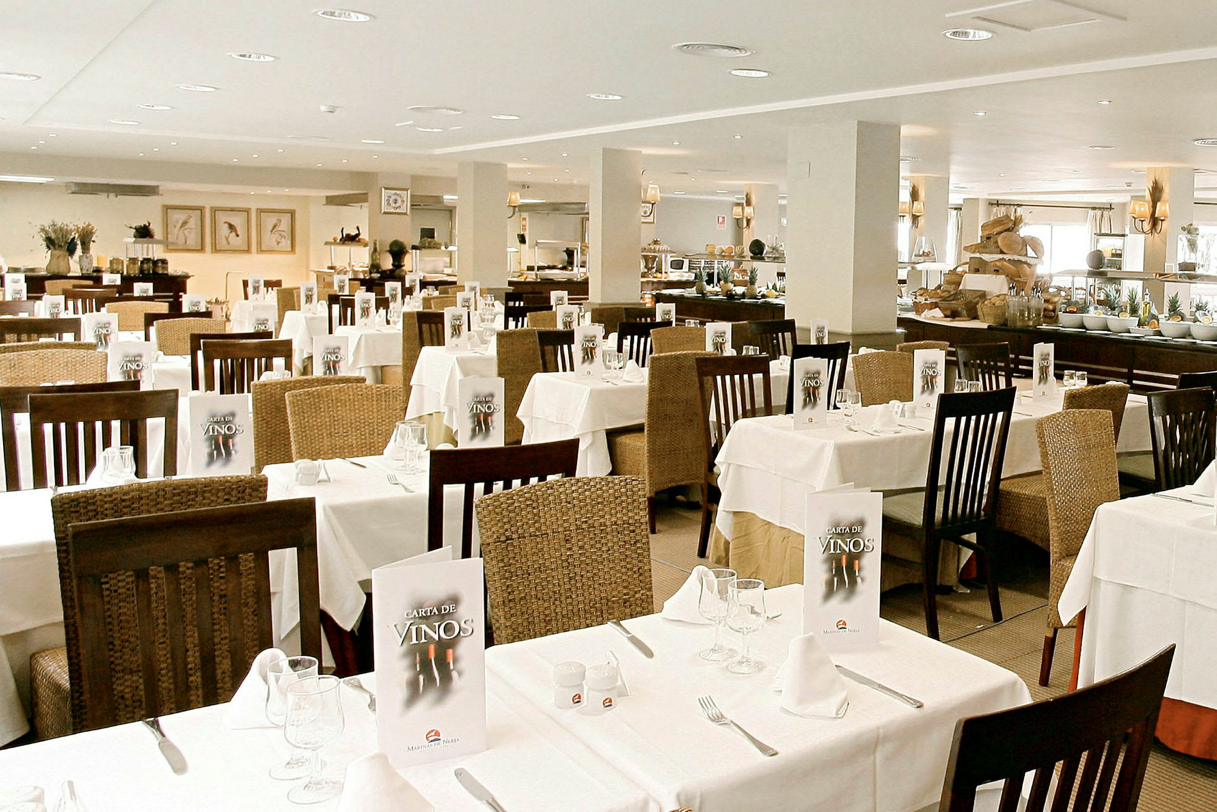 En ljus restaurang med dukade bord och stolar, menyer på borden och en buffé i bakgrunden. (AI-genererad text)