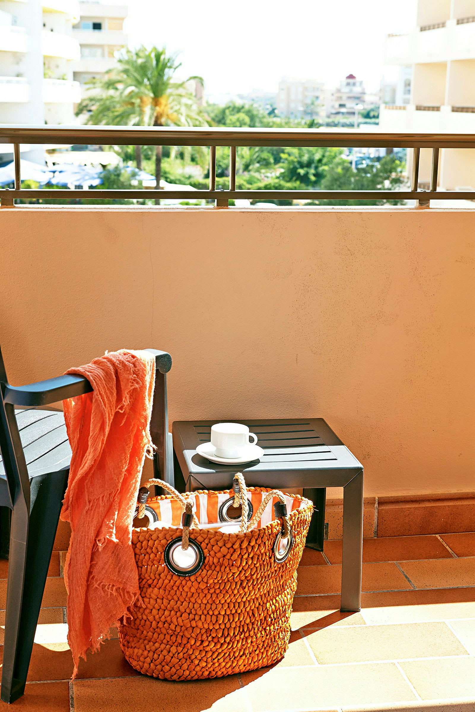 En balkong med en stol, ett bord med en kaffekopp och en orange väska på golvet. (AI-genererad text)