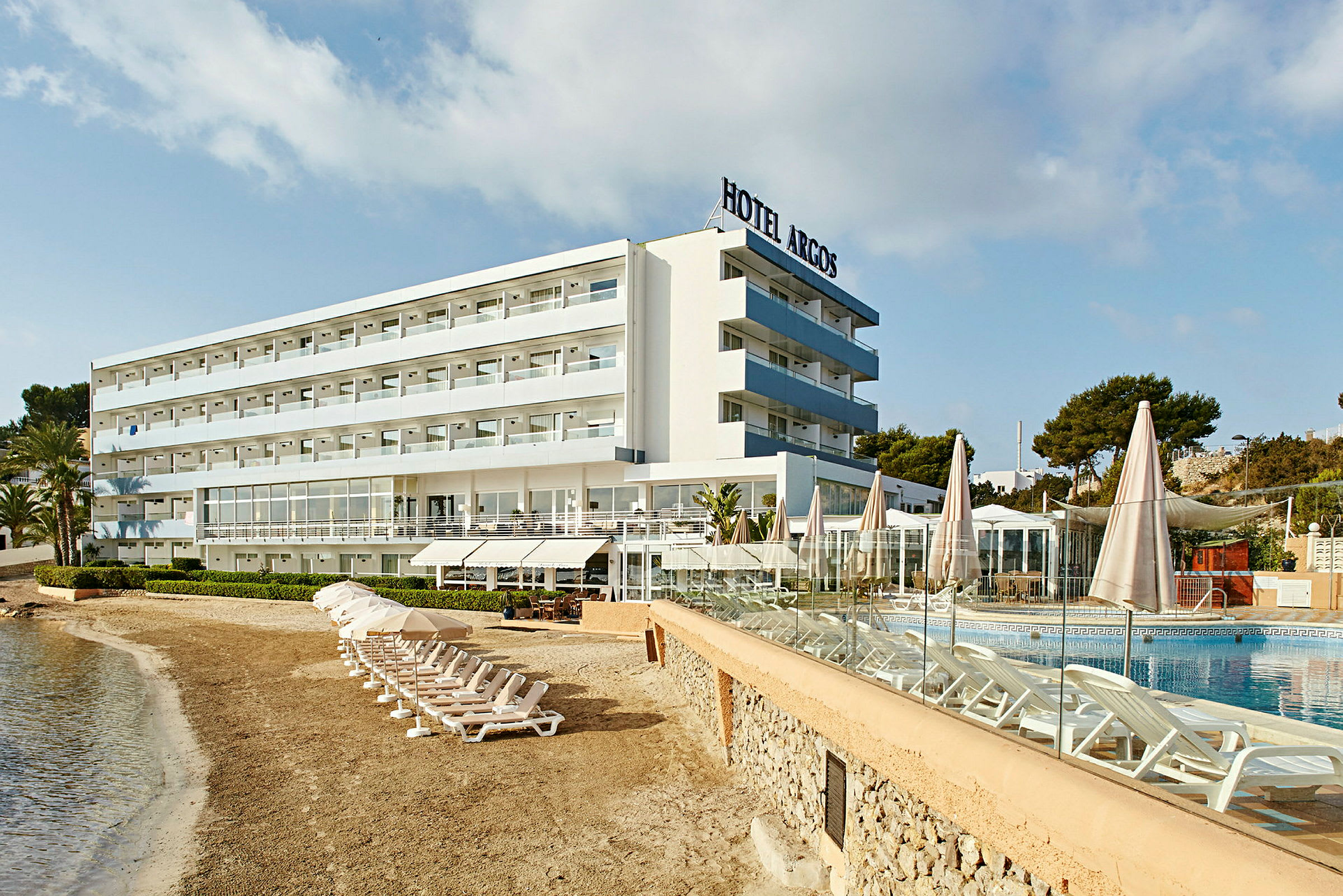 Ett hotell vid stranden med solstolar vid poolen. (AI-genererad text)