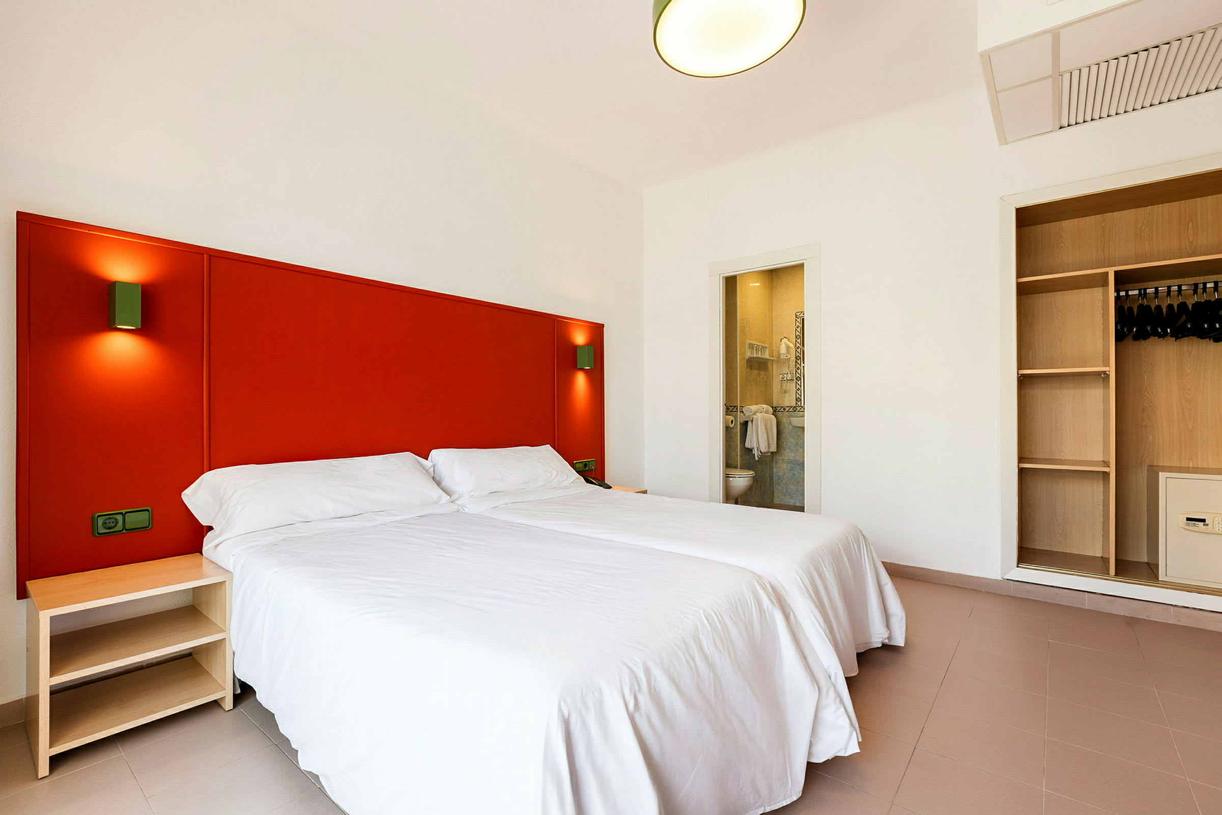 Hotellrum med två enkelsängar, en garderob och ett öppet badrum. (AI-genererad text)