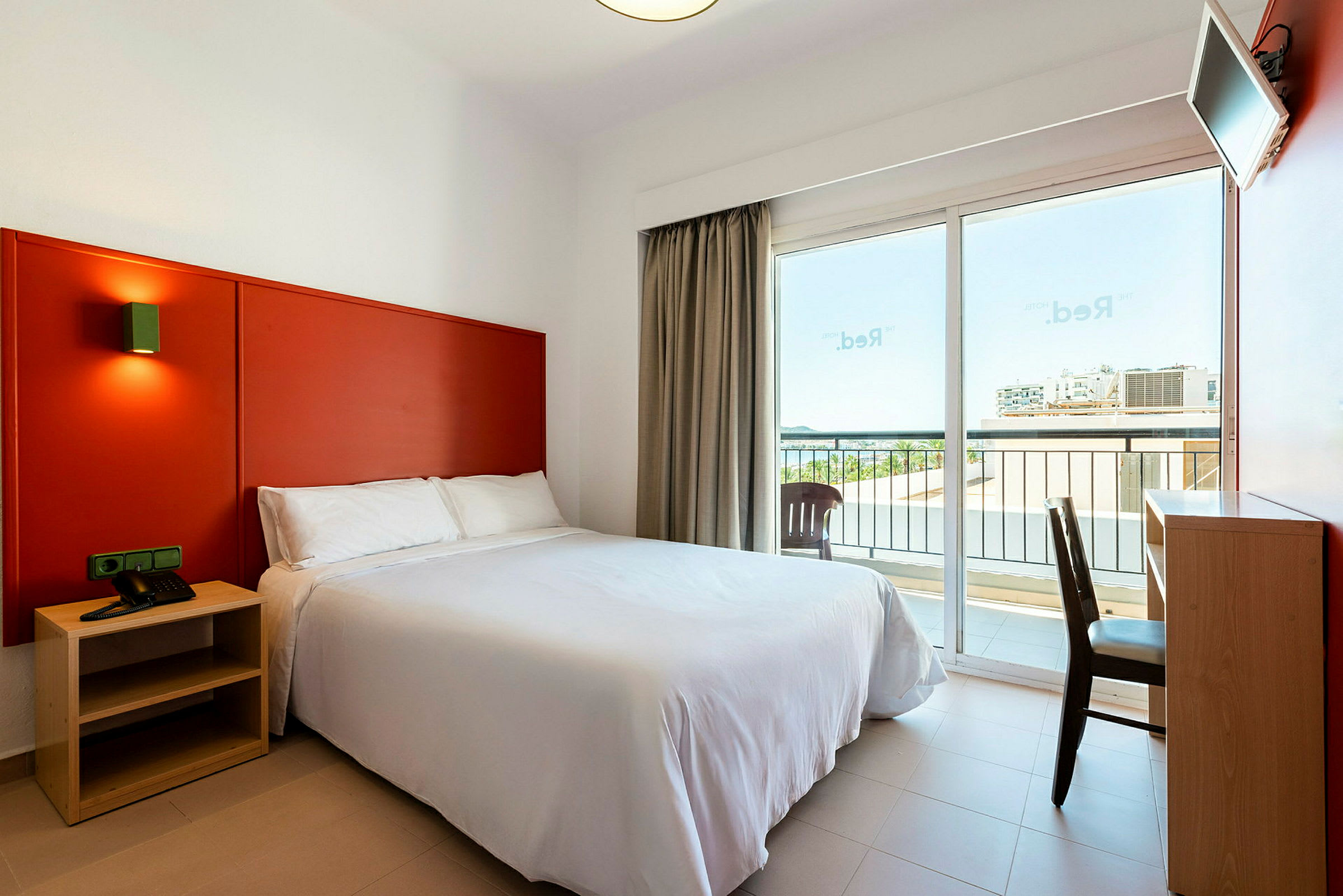Hotellrum med en dubbelsäng, ett skrivbord och en balkong. (AI-genererad text)