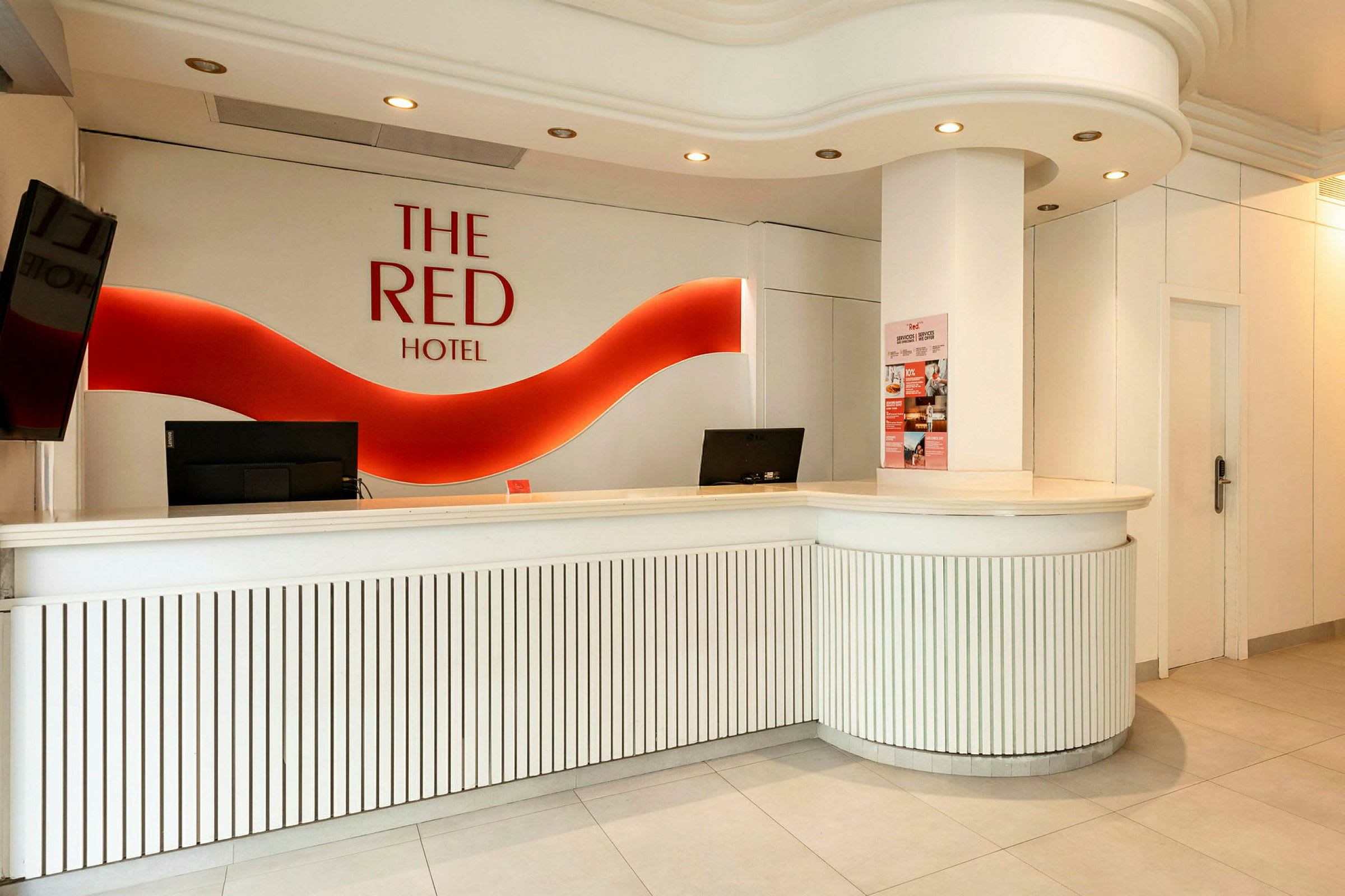 Hotellreception med vit inredning och röd logotyp på väggen. (AI-genererad text)