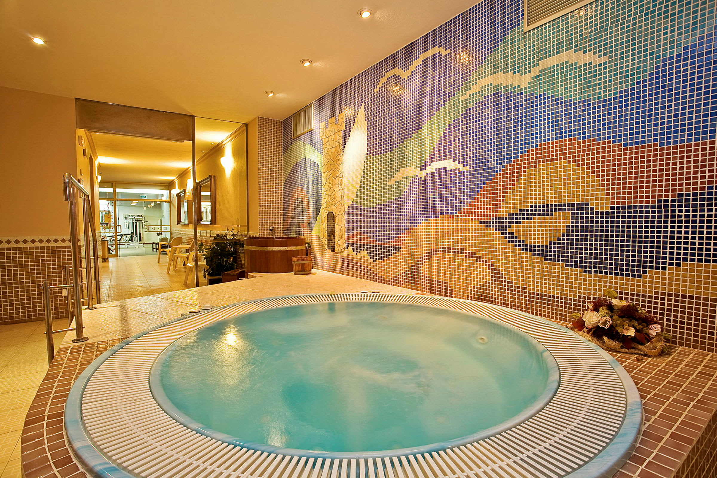 En jacuzzi i ett spa med en färgglad mosaikvägg som bakgrund. (AI-genererad text)