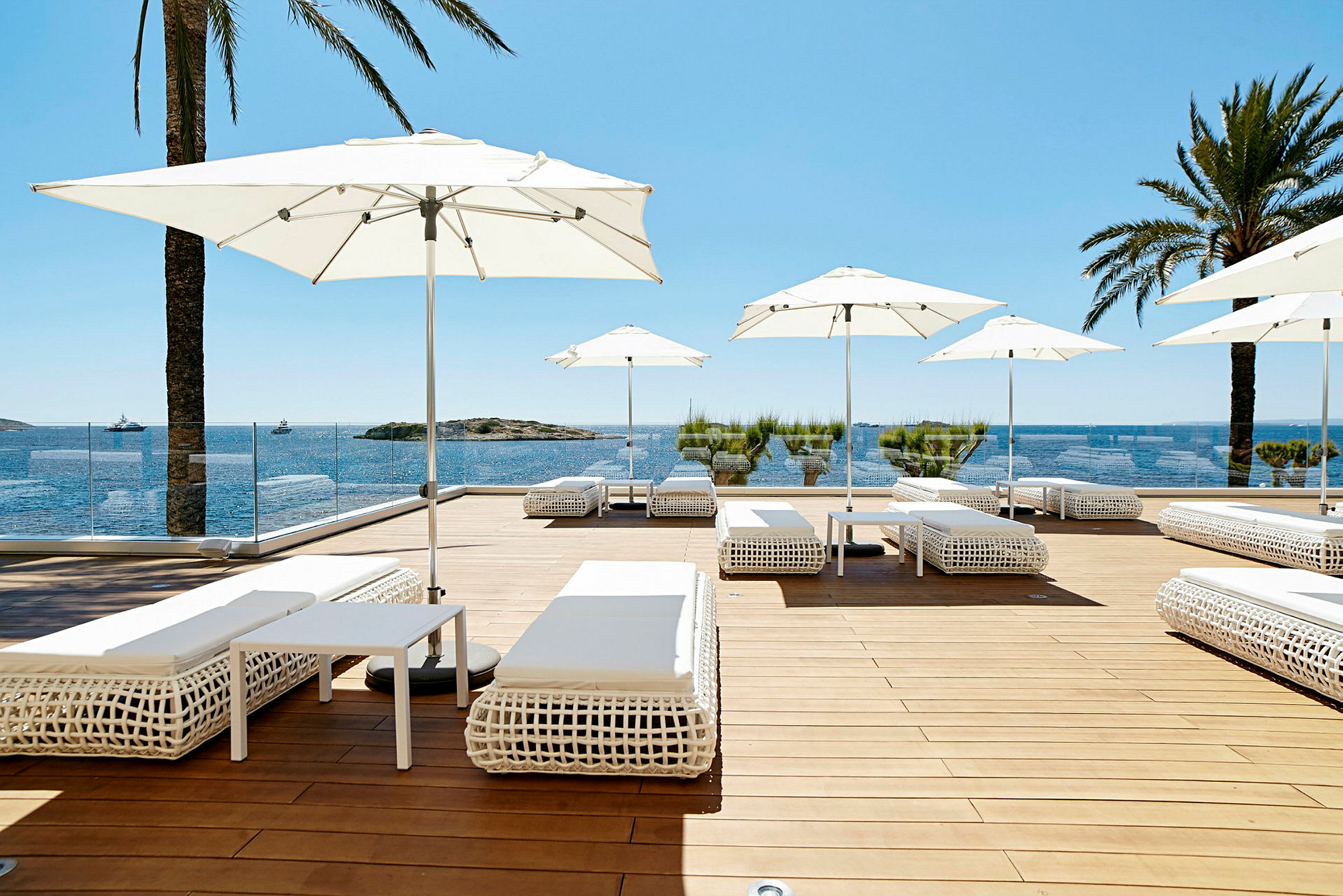 Solterrass med vita solsängar och parasoll, utsikt över havet och blå himmel. (AI-genererad text)