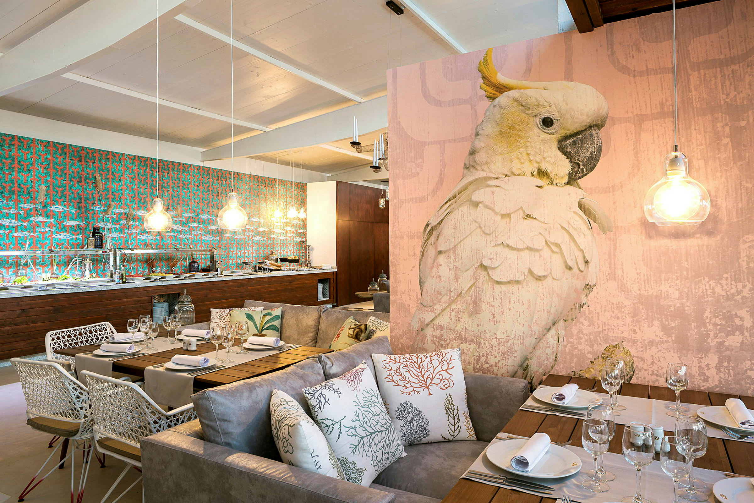 En elegant inredd restaurang med ett stort fågelmotiv, dämpad belysning och en matplats med soffor och kuddar. (AI-genererad text)