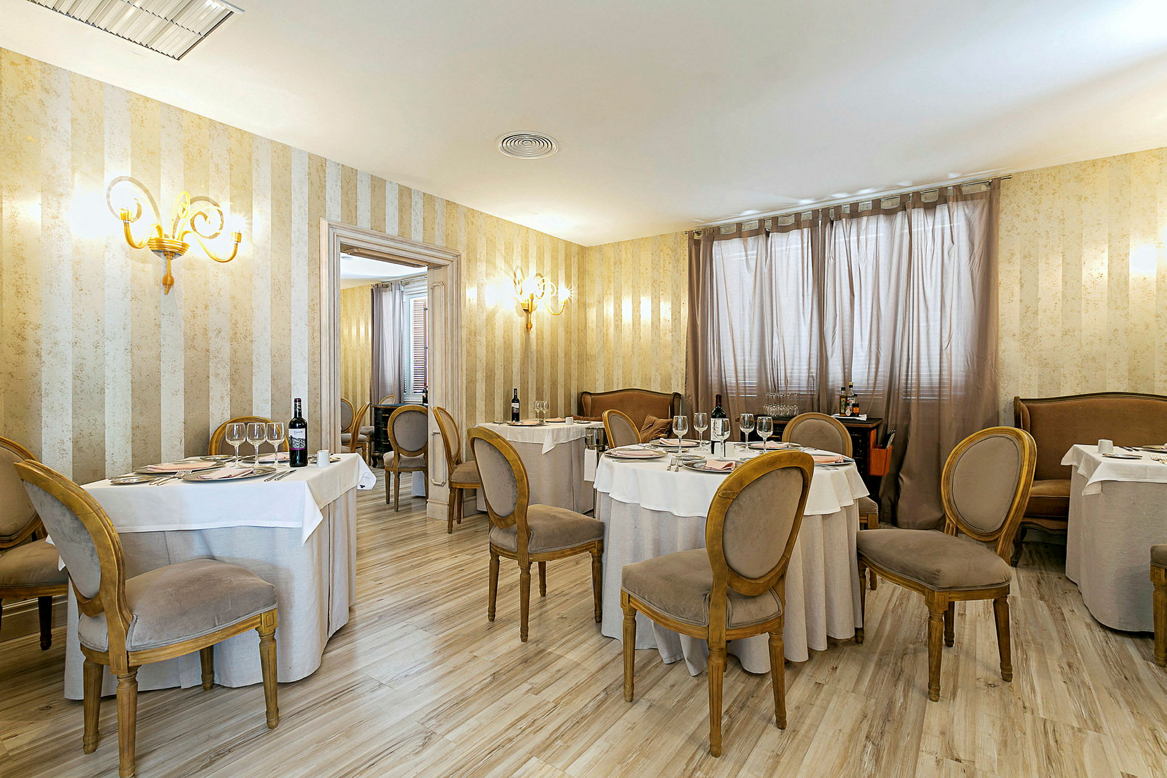Ett elegant inrett restaurangrum med runda dukade bord och stolar i klassisk stil. (AI-genererad text)