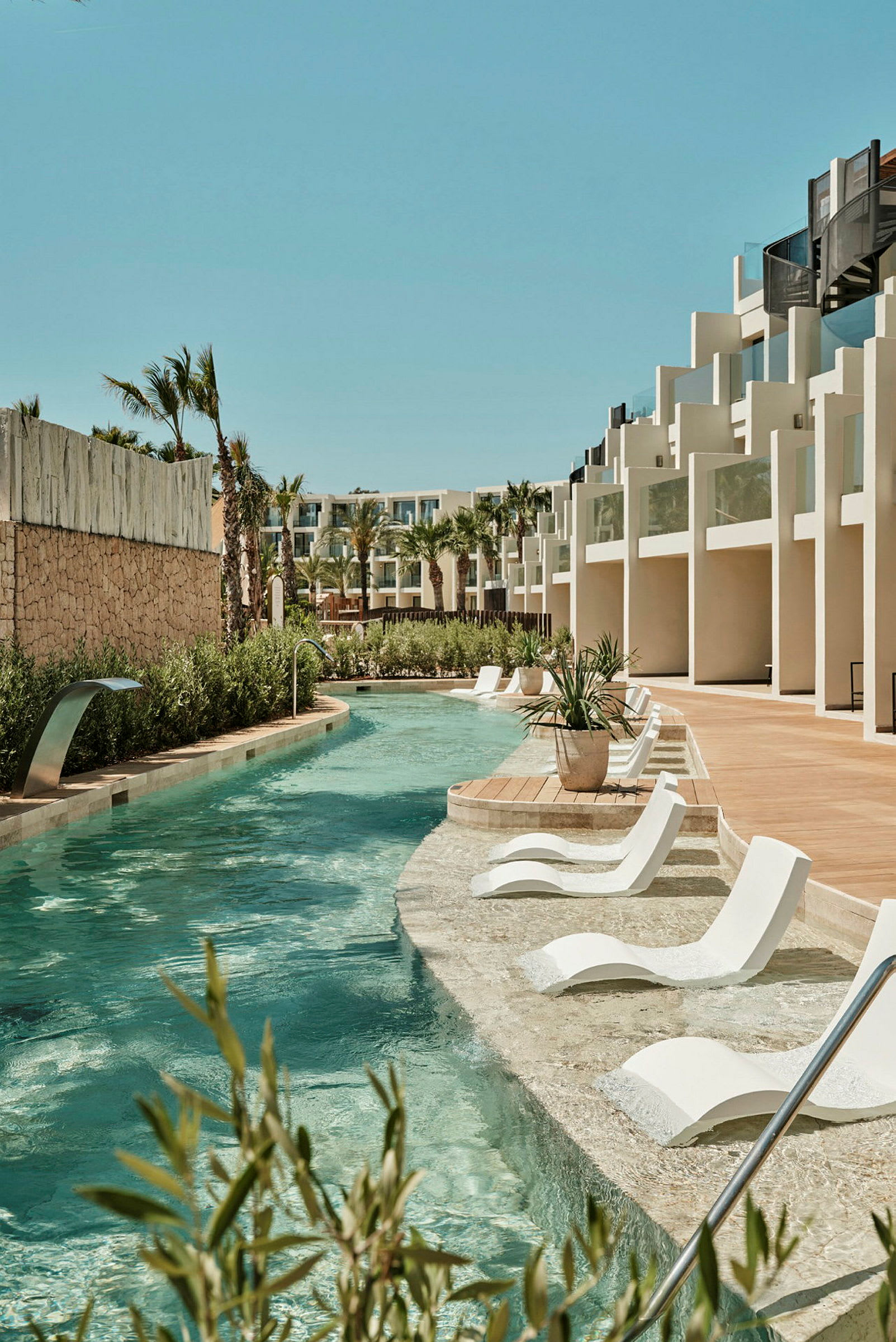 En pool med solstolar och modern byggnadsdesign i bakgrunden. (AI-genererad text)