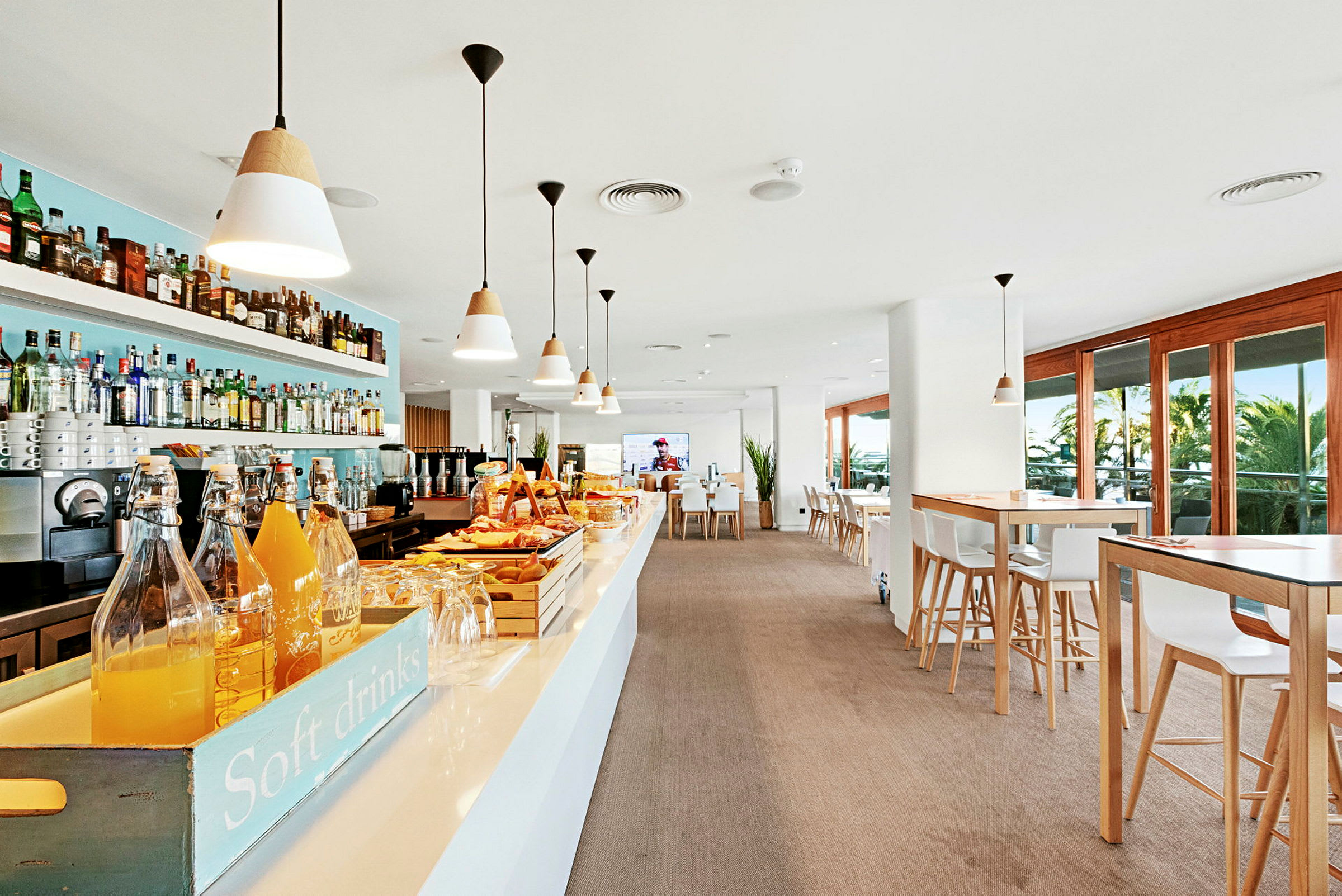 Interiörbild av en modern bar och café med bord, stolar och stora fönster och en serveringsdisk. (AI-genererad text)