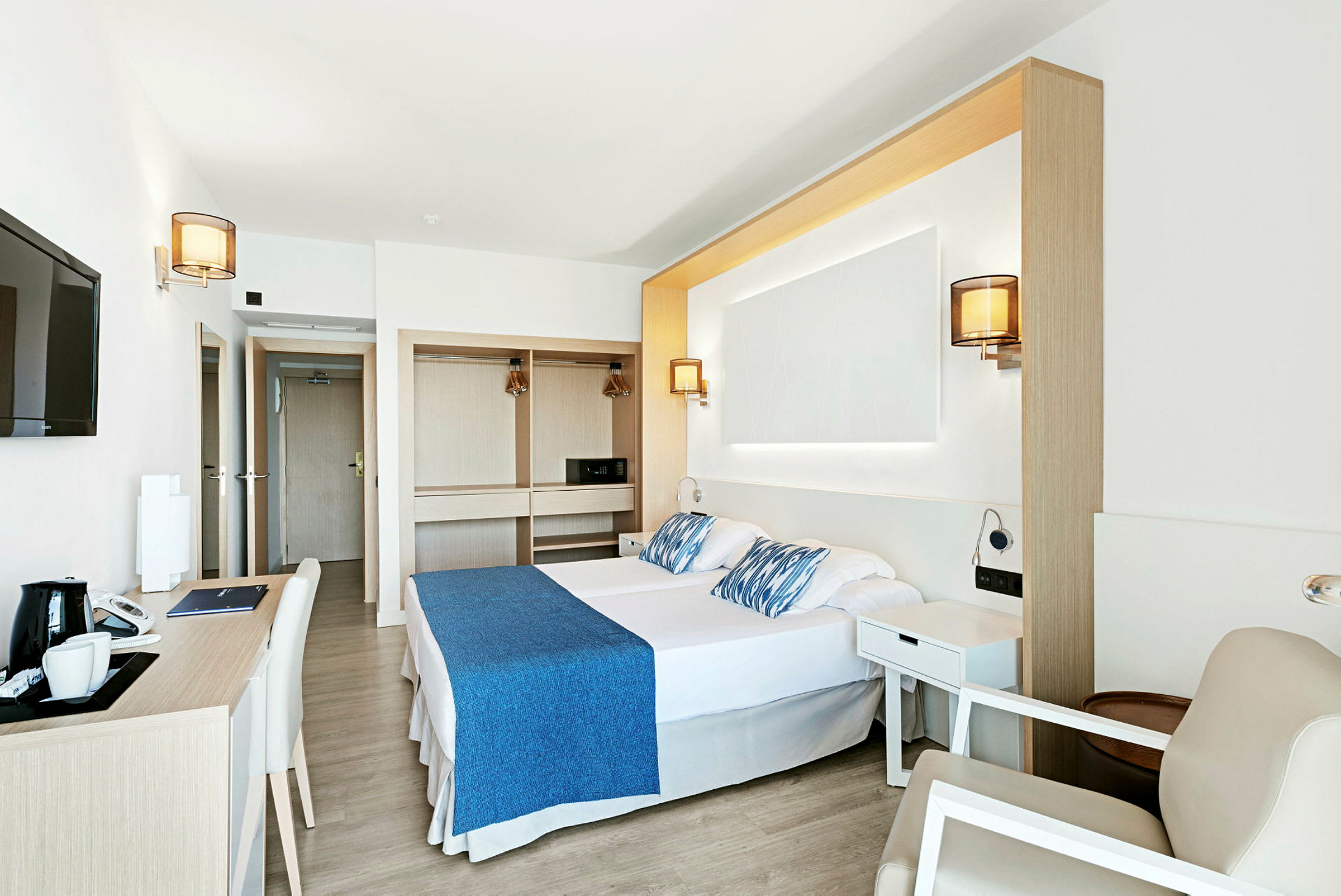 Ett ljust och modernt hotellrum med dubbelsäng, skrivbord, och garderob. (AI-genererad text)