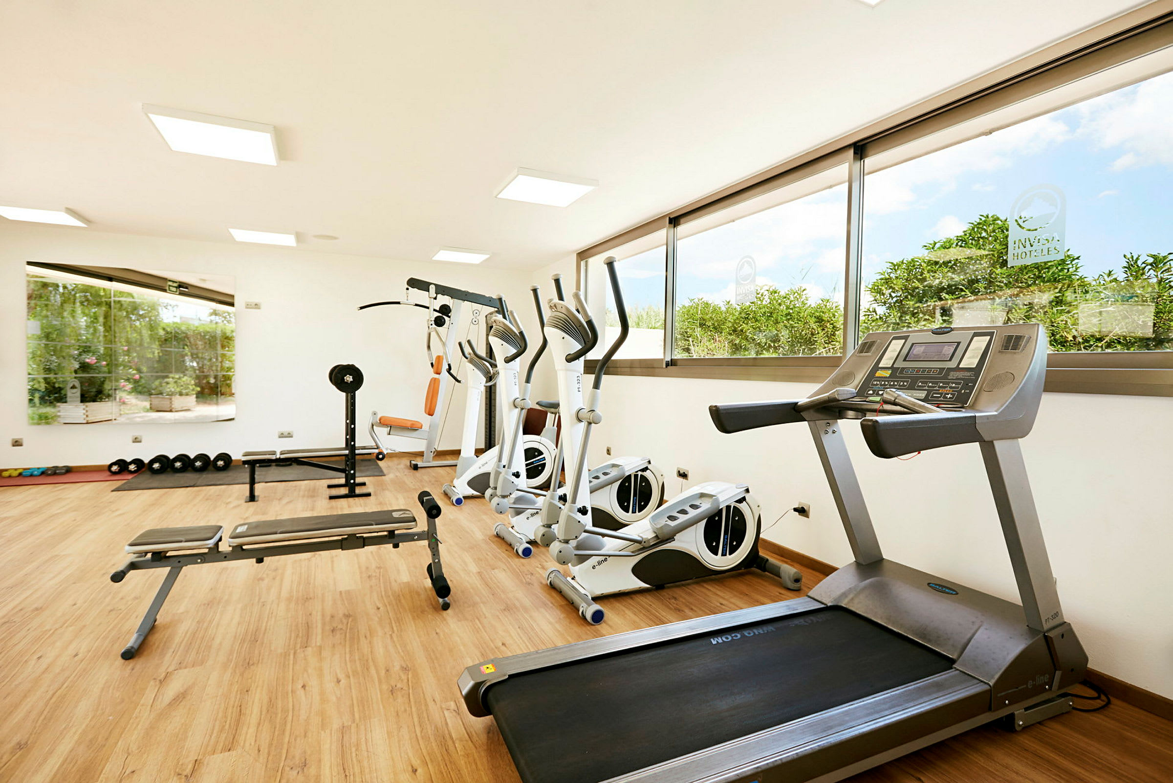 Ett gym med träningsmaskiner, löpband och vikter på ett trägolv. (AI-genererad text)
