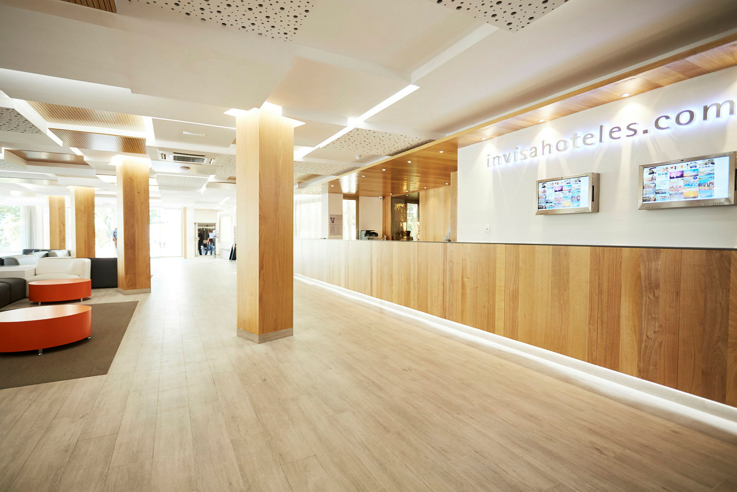 Receptionen i en modern lobby, med trägolv och pelare samt en informationsdisk. (AI-genererad text)