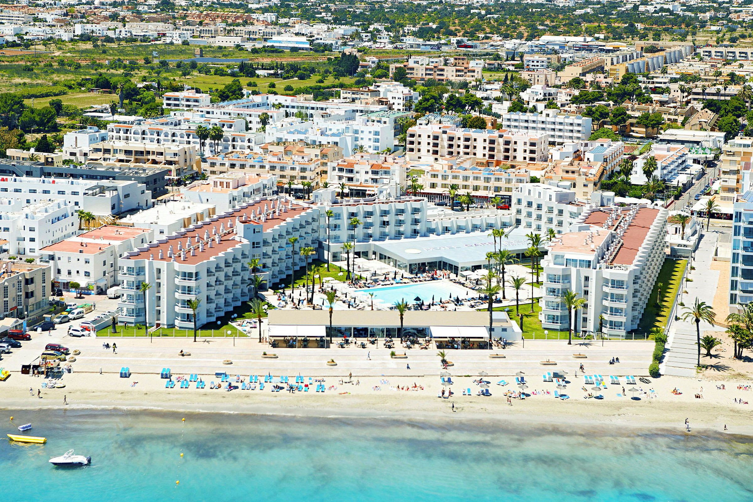 Flygfoto över en kuststad med ett hotellkomplex framför stranden. (AI-genererad text)