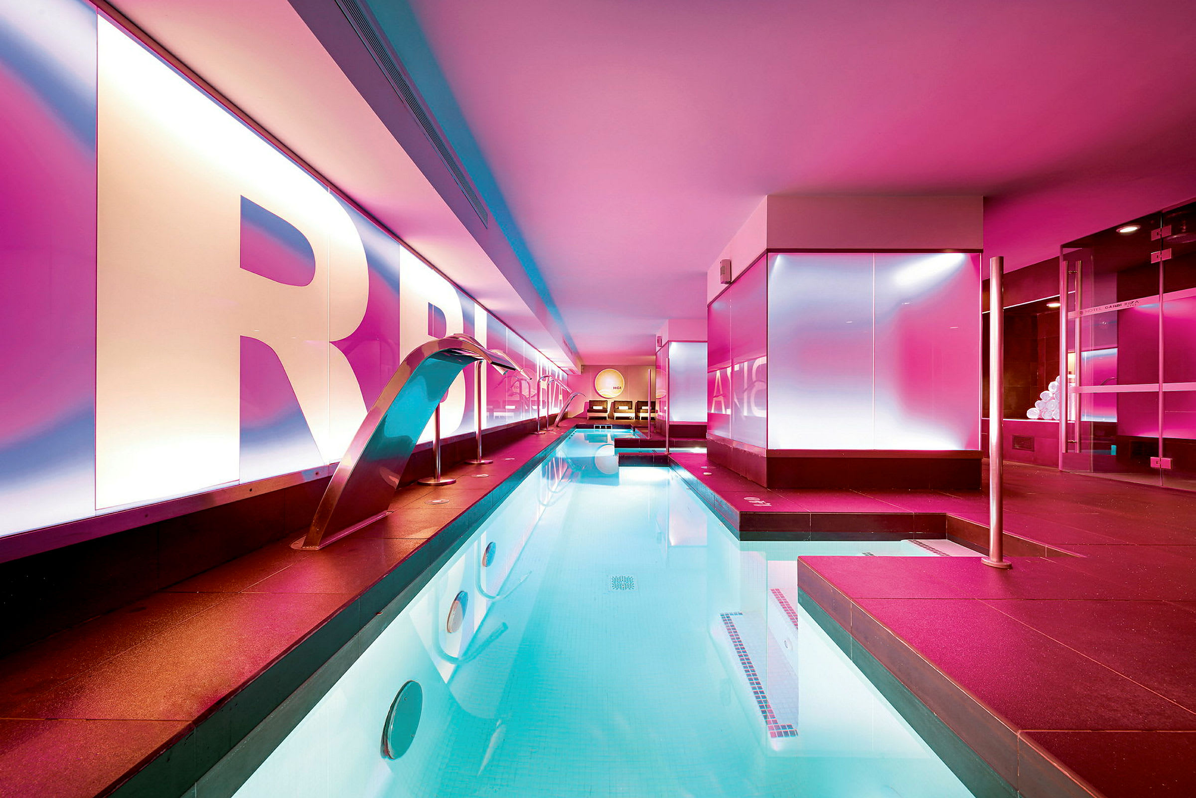 Bild av en inomhuspool med modern belysning och rosa-ljus design. (AI-genererad text)