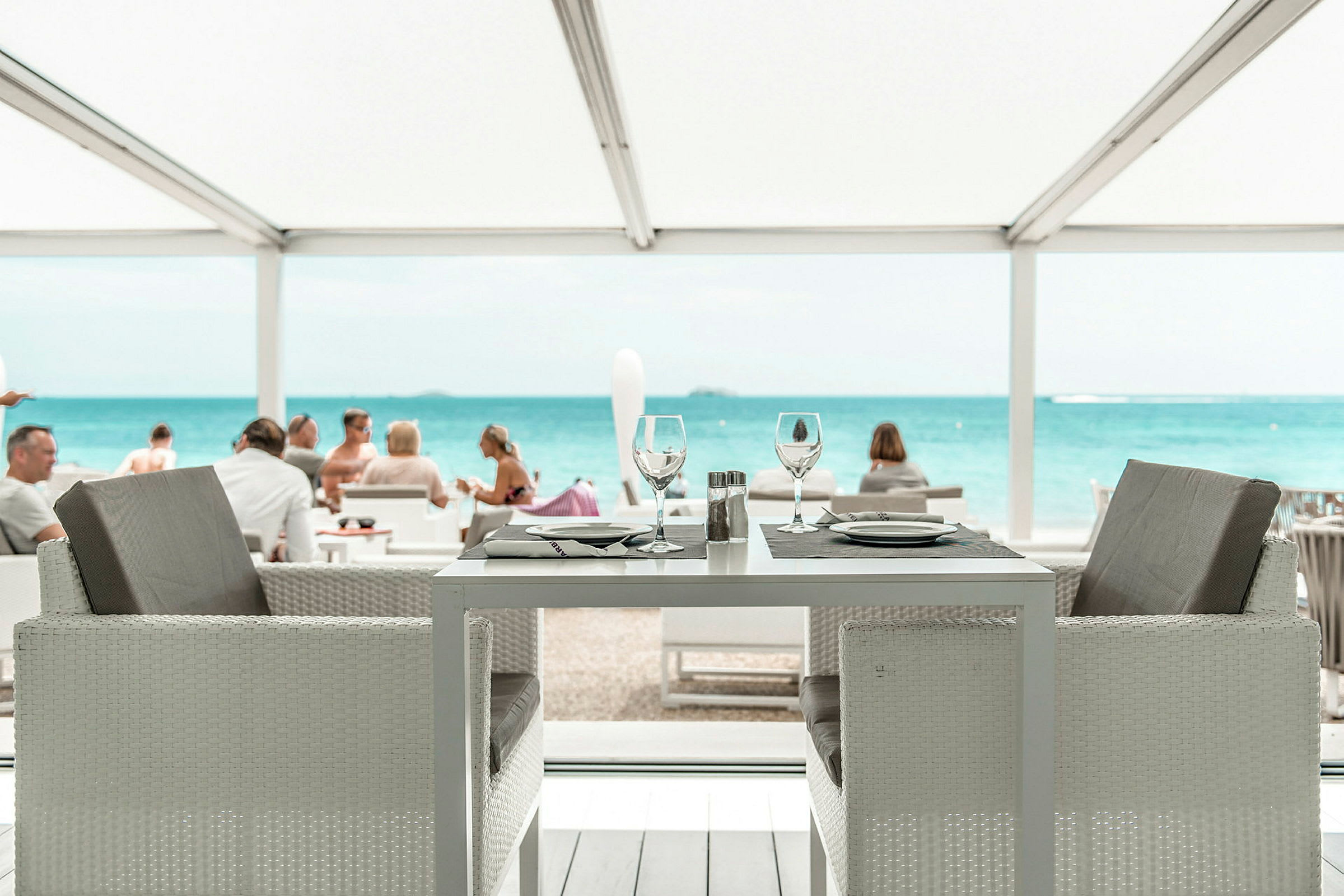 En dukad restaurangplats med utsikt över havet och en strand. (AI-genererad text)