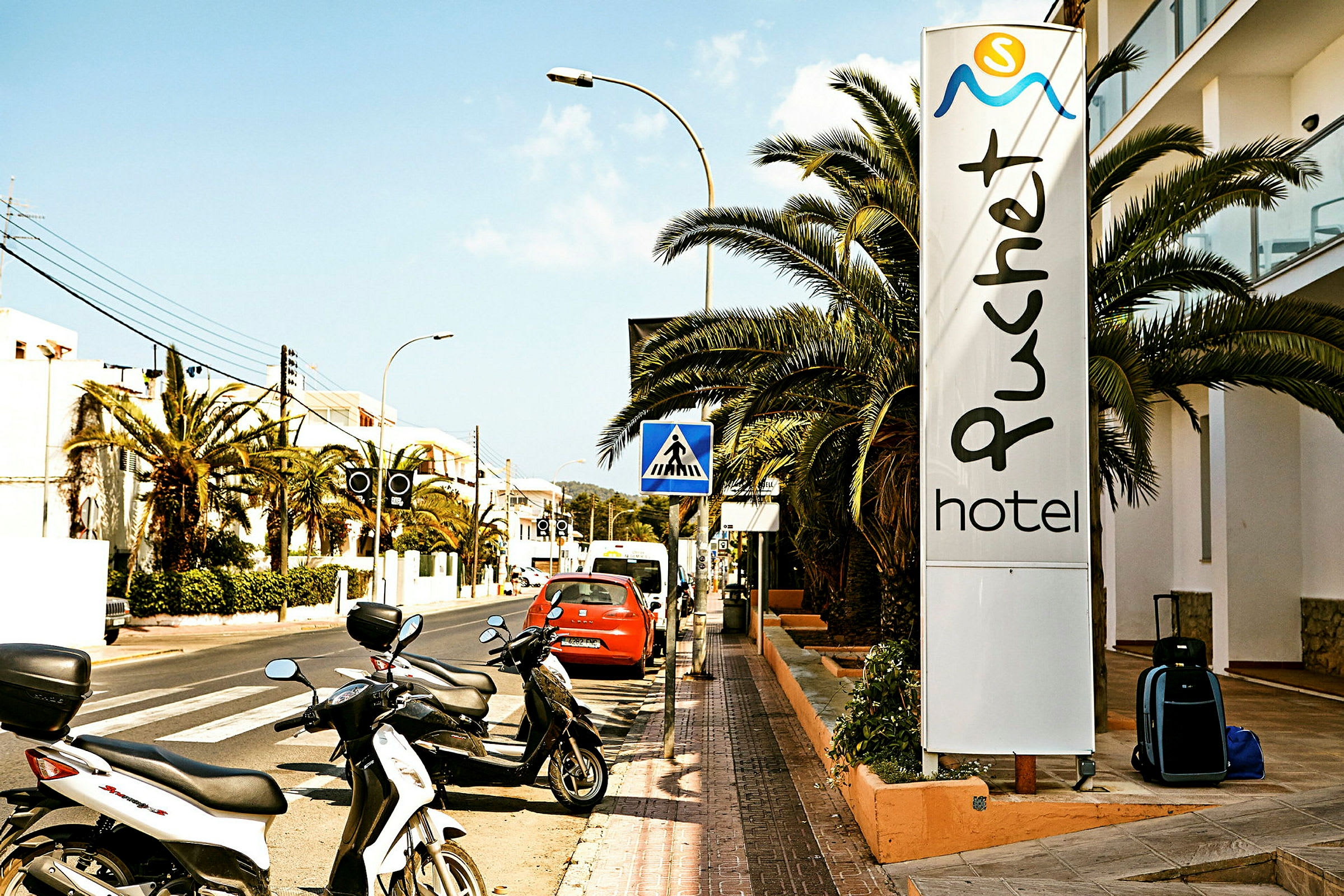Gata med parkerade motorcyklar och en skylt som visar "Puchet Hotel". (AI-genererad text)