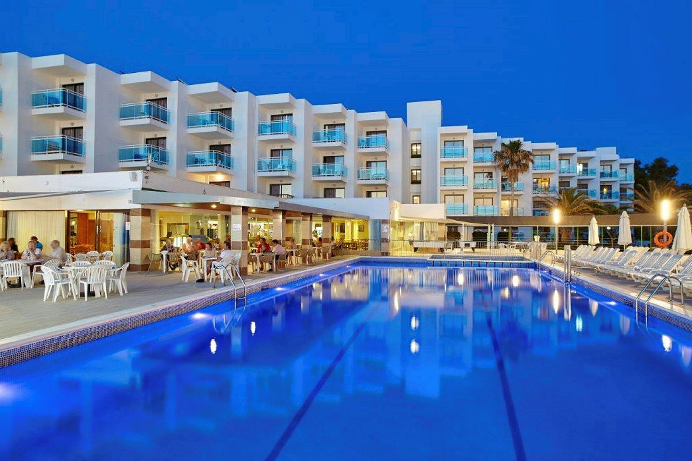 Hotell med pool och uteservering i skymningen. (AI-genererad text)