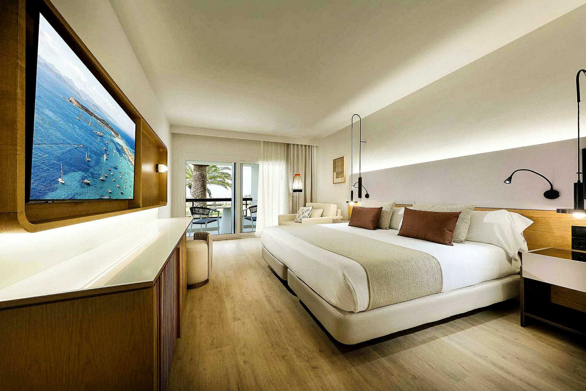 Hotellrum med stor säng, väggmonterad TV och sittplats vid balkongen. (AI-genererad text)