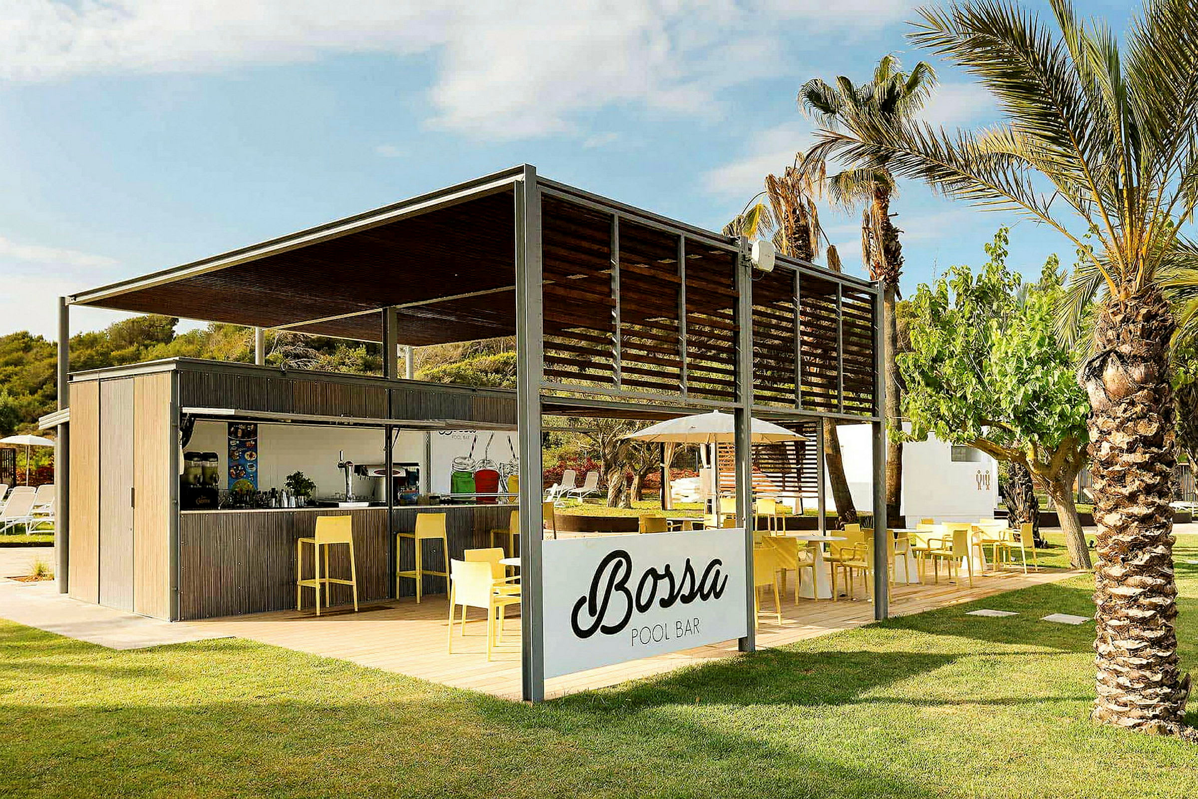 En utomhuspoolbar med skyltning som lyder 'Bossa Pool Bar', omgiven av grönska och palmer. Det finns sittplatser med gula stolar och bord. (AI-genererad text)