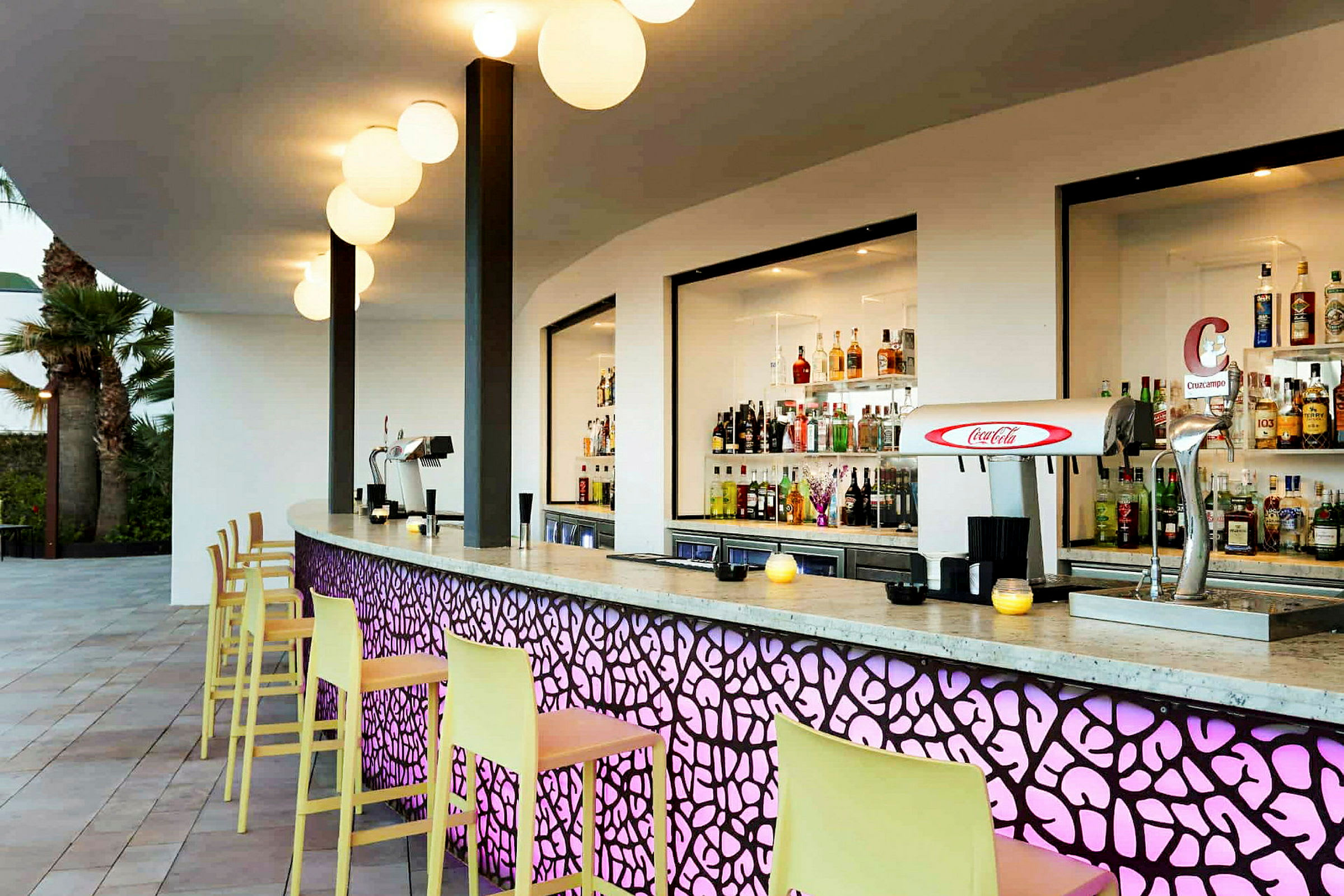 En modern bar med färgglada detaljer och sortiment av drycker bakom disken. (AI-genererad text)