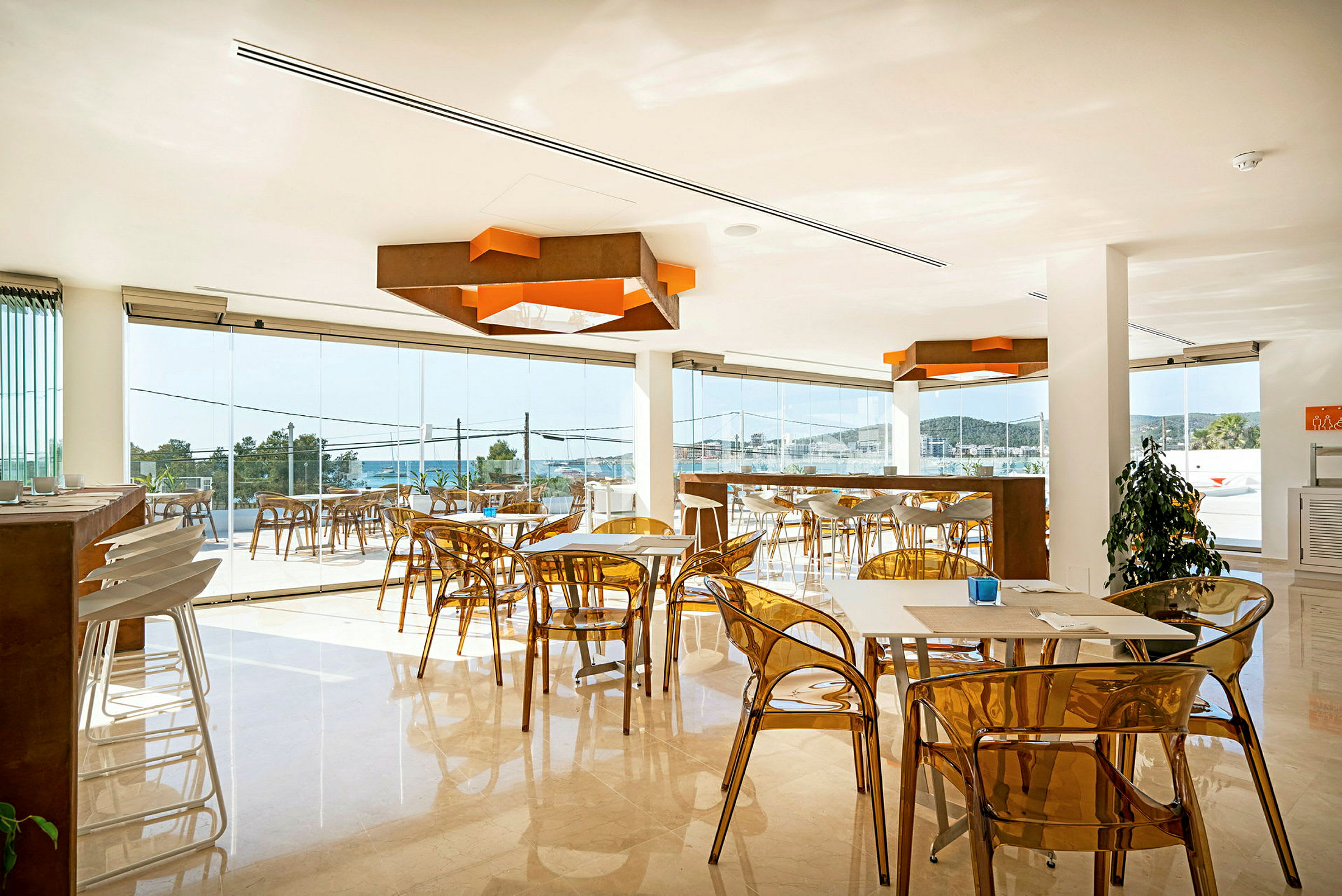 Ett modernt kafé med genomskinliga stolar och fönster med utsikt mot havet. (AI-genererad text)