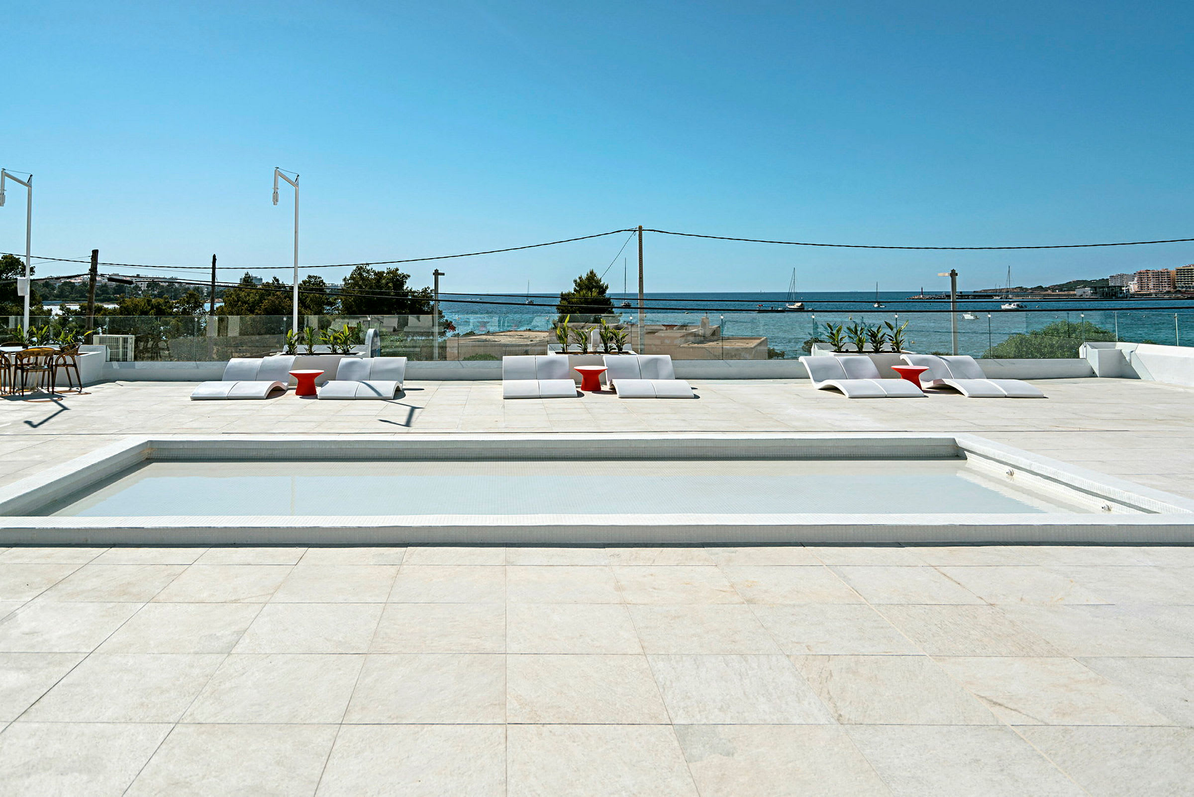 Solterass med pool, solstolar och utsikt över havet. (AI-genererad text)