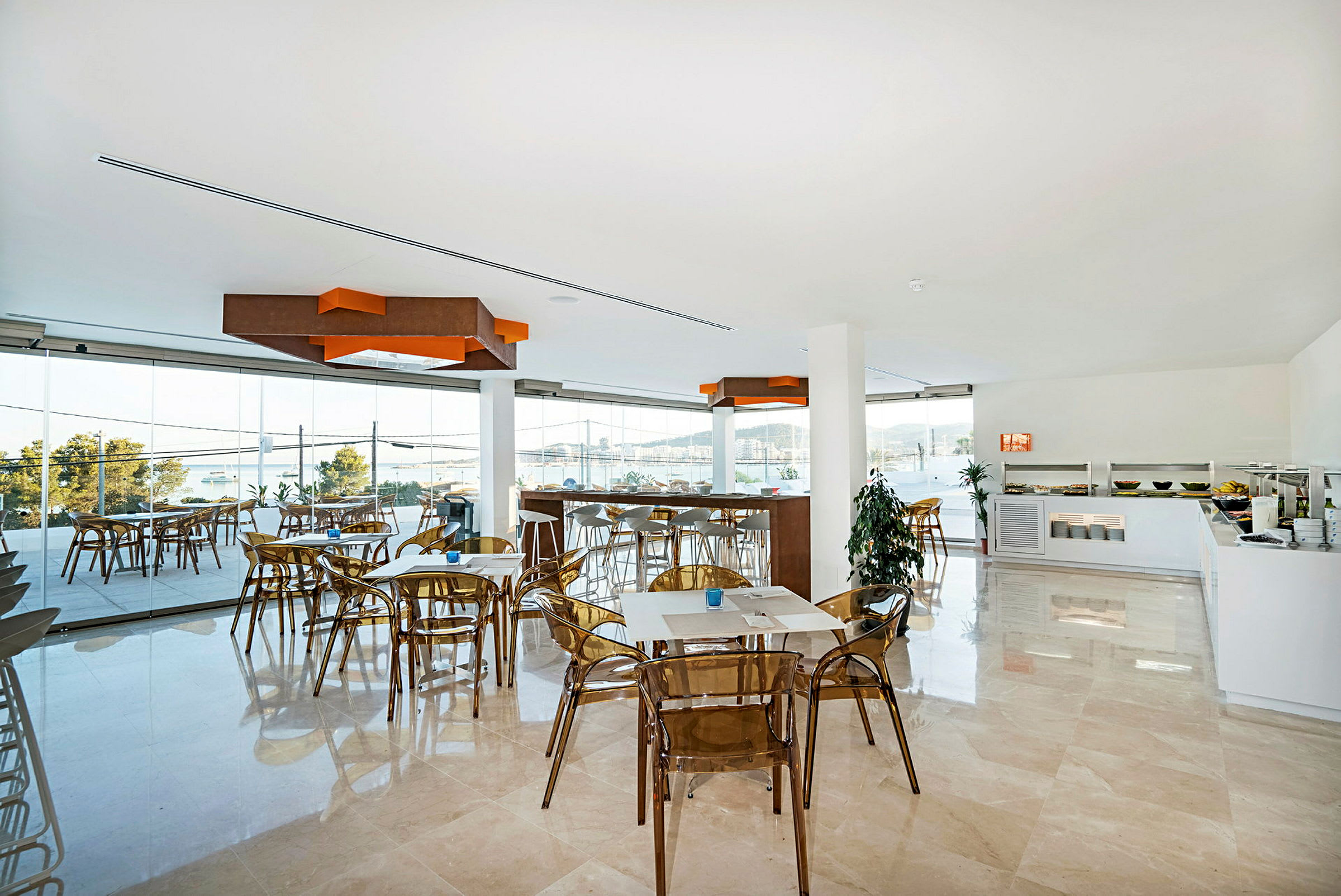 Interiör av en ljus restaurang med glasväggar och utsikt över vatten och landskap. (AI-genererad text)