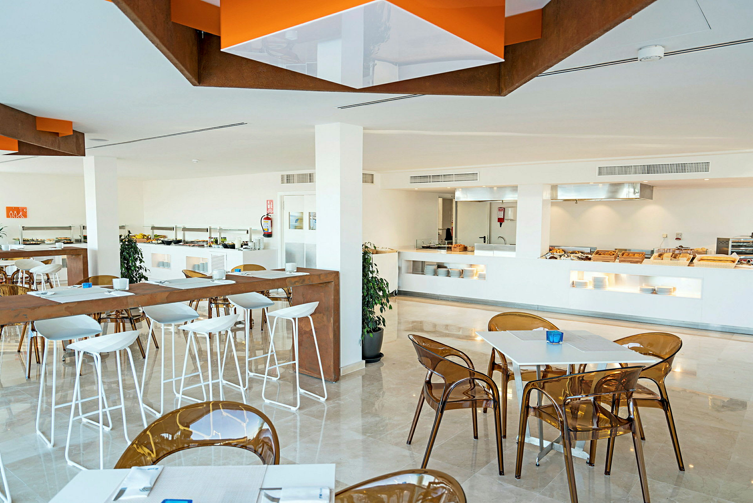 En modern restaurang med vita bord och stolar. En buffésektion syns i bakgrunden. (AI-genererad text)
