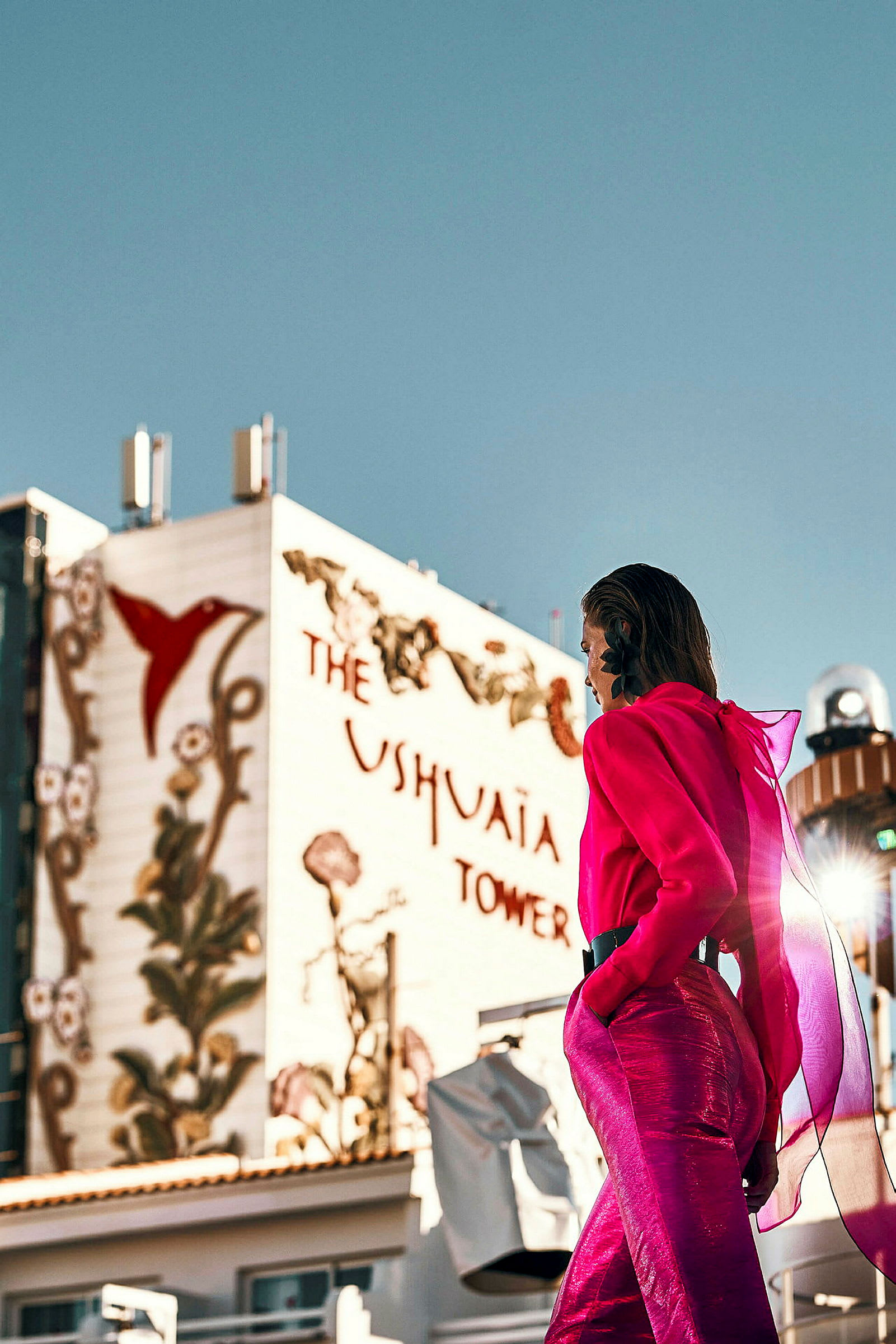 En person i en rosa outfit framför en byggnad med texten 'Ushuaia Tower' och dekorationer. (AI-genererad text)
