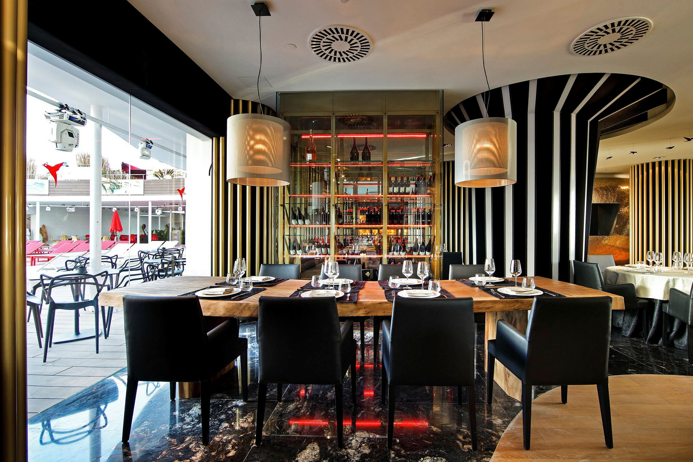 Interiör av en modern restaurang med träbord och svarta stolar, omgiven av randiga väggdekorationer och stora fönster. (AI-genererad text)
