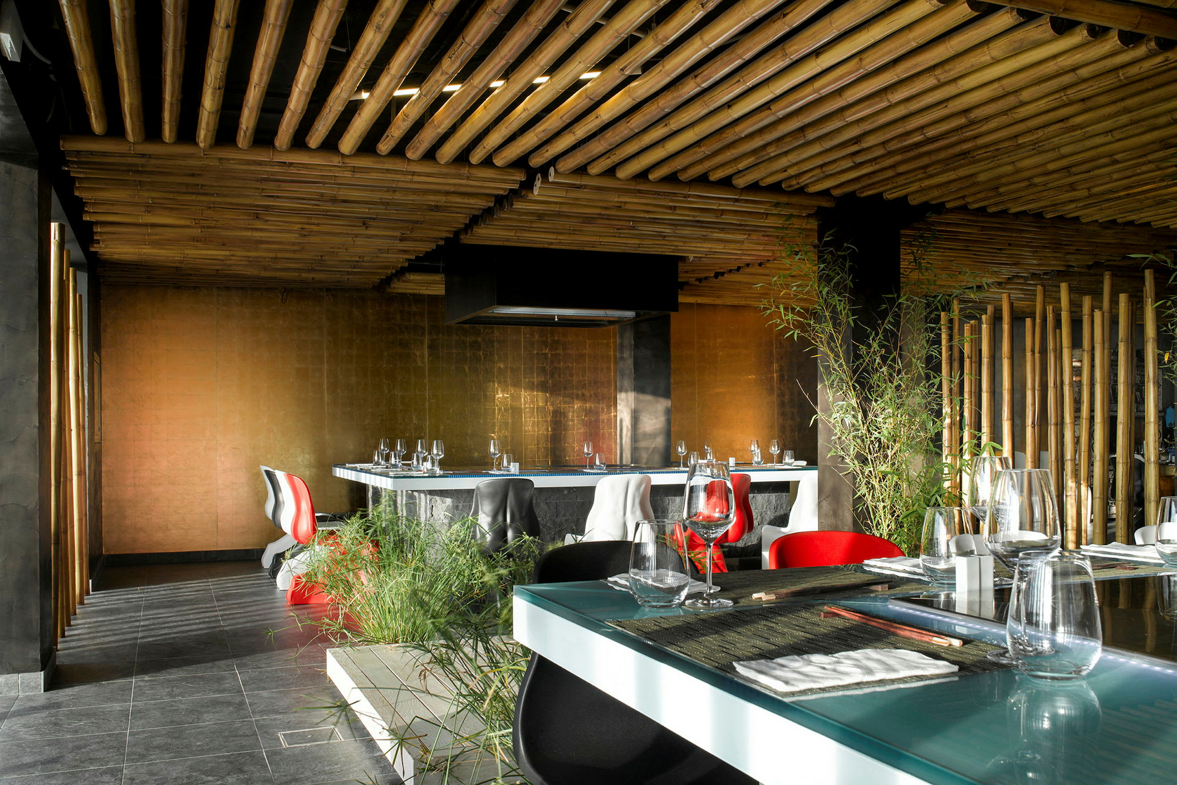 Interiör av en modern restaurang med bambuinspirerat tak, eleganta möbler och gröna växter. (AI-genererad text)