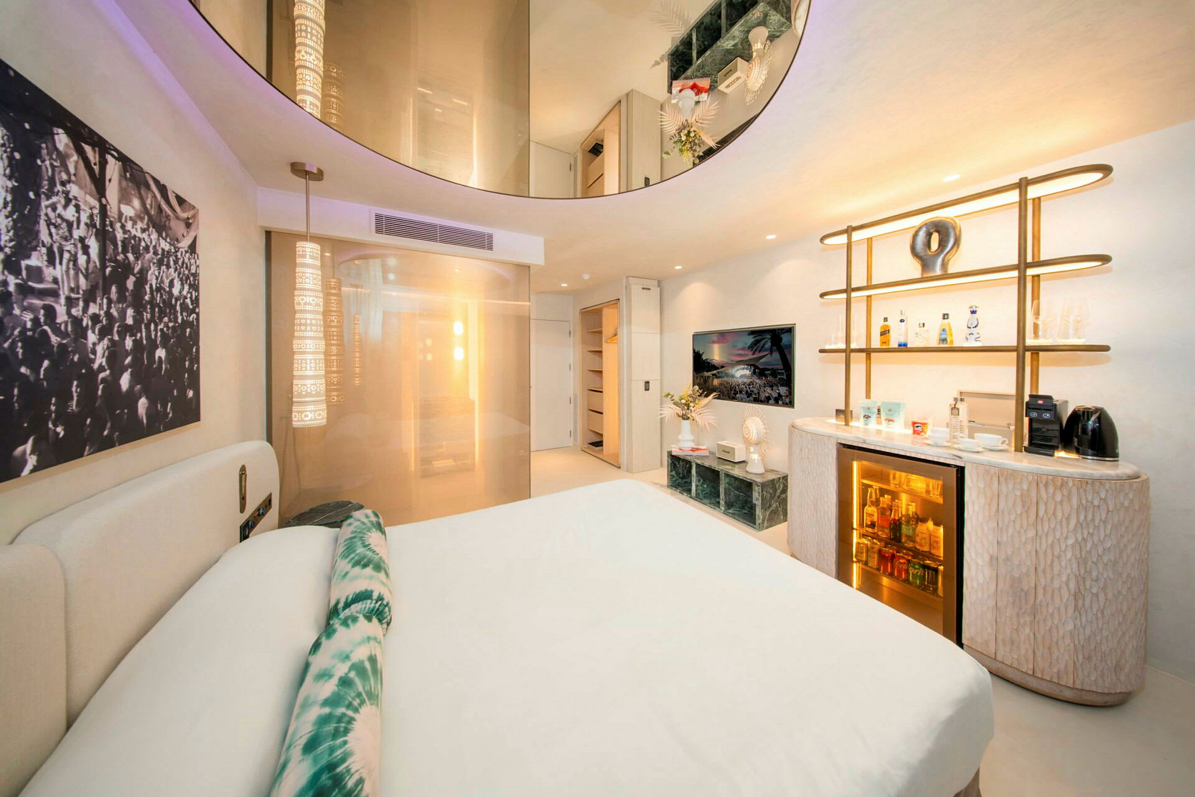 Ett modernt hotellrum med en dubbelsäng, dekorativa belysningar och ett minibarområde. (AI-genererad text)