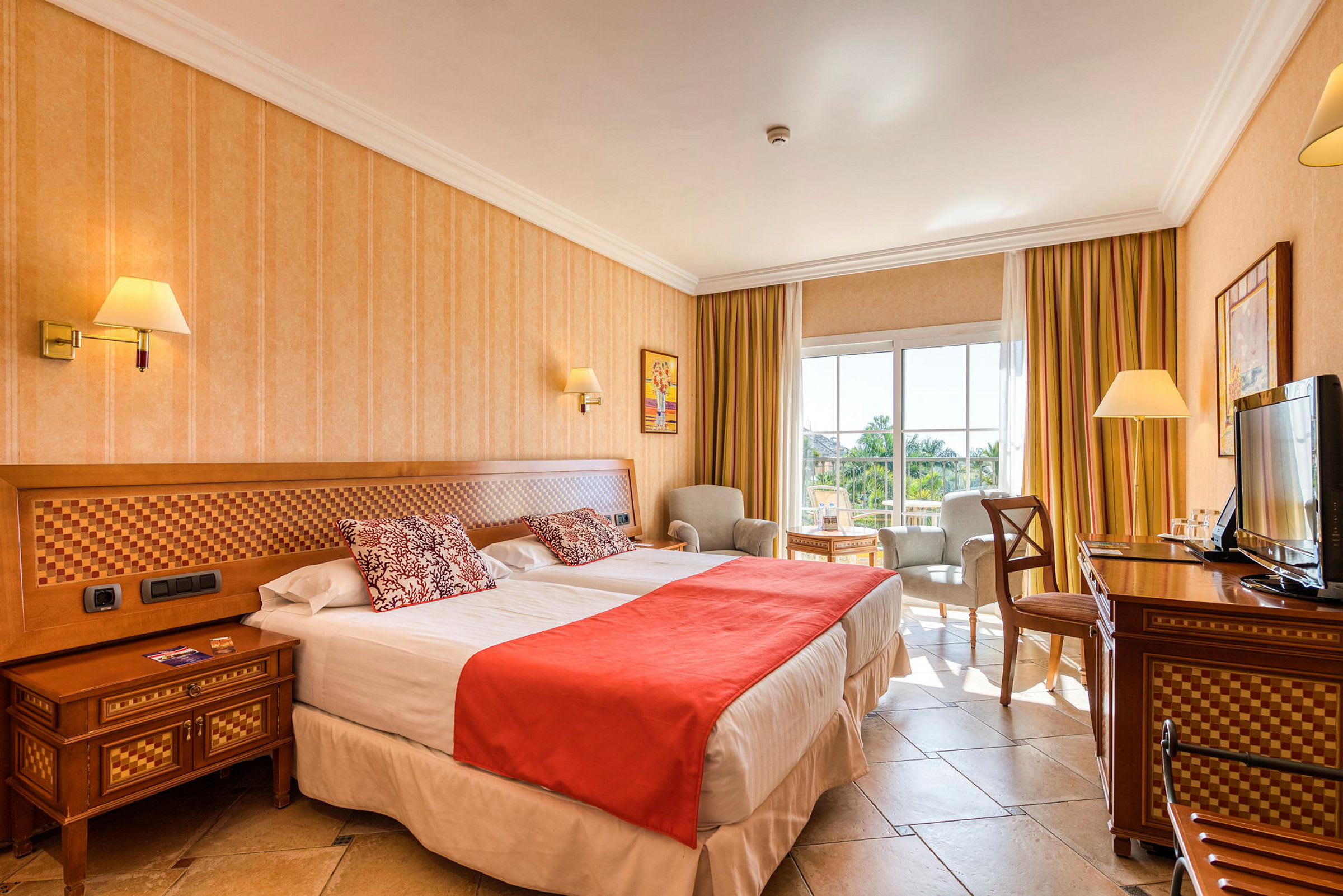 Bild på ett hotellrum med två sängar, stol och bord, samt en TV. (AI-genererad text)