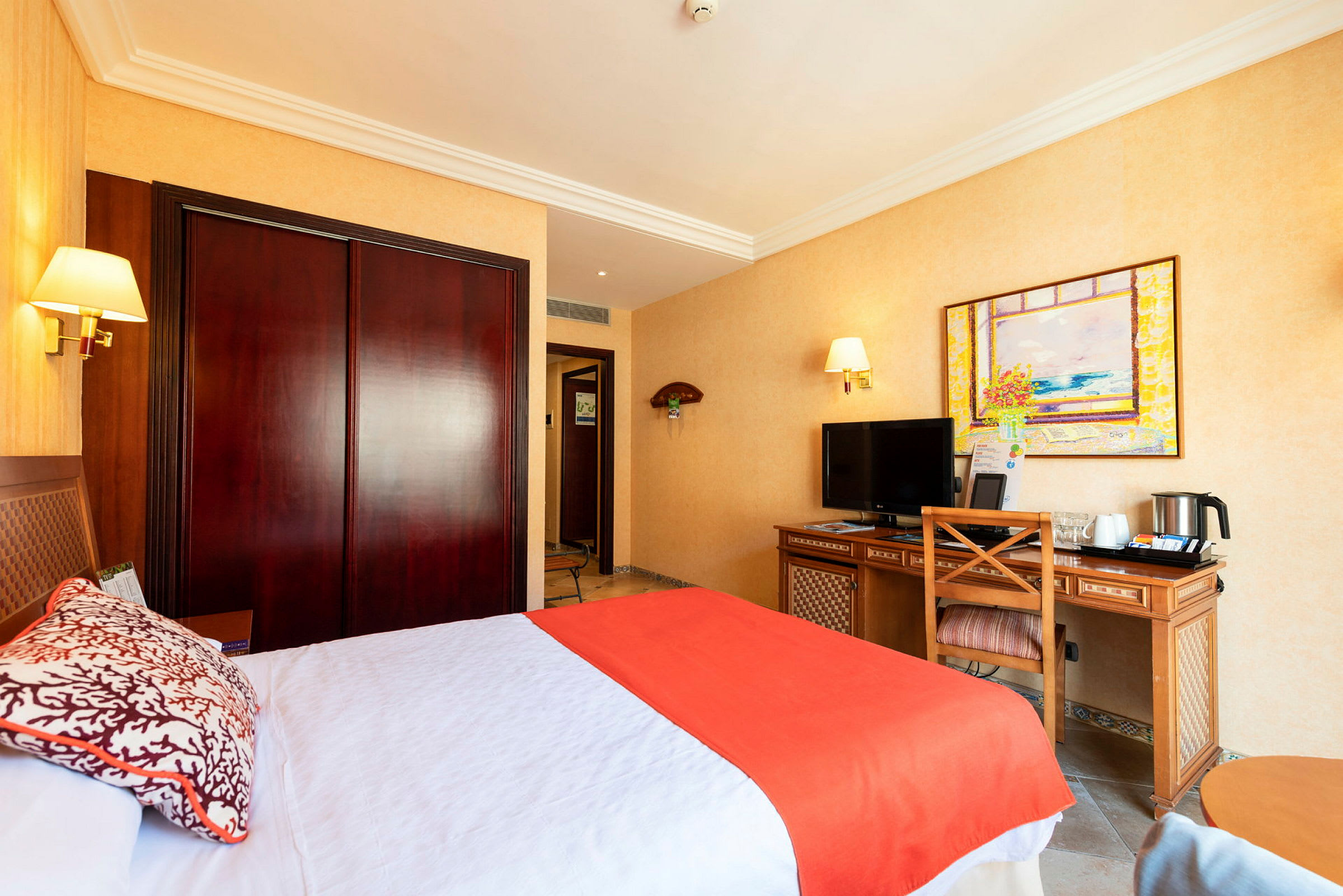 Ett hotellrum med en säng, skrivbord, TV och garderob. (AI-genererad text)