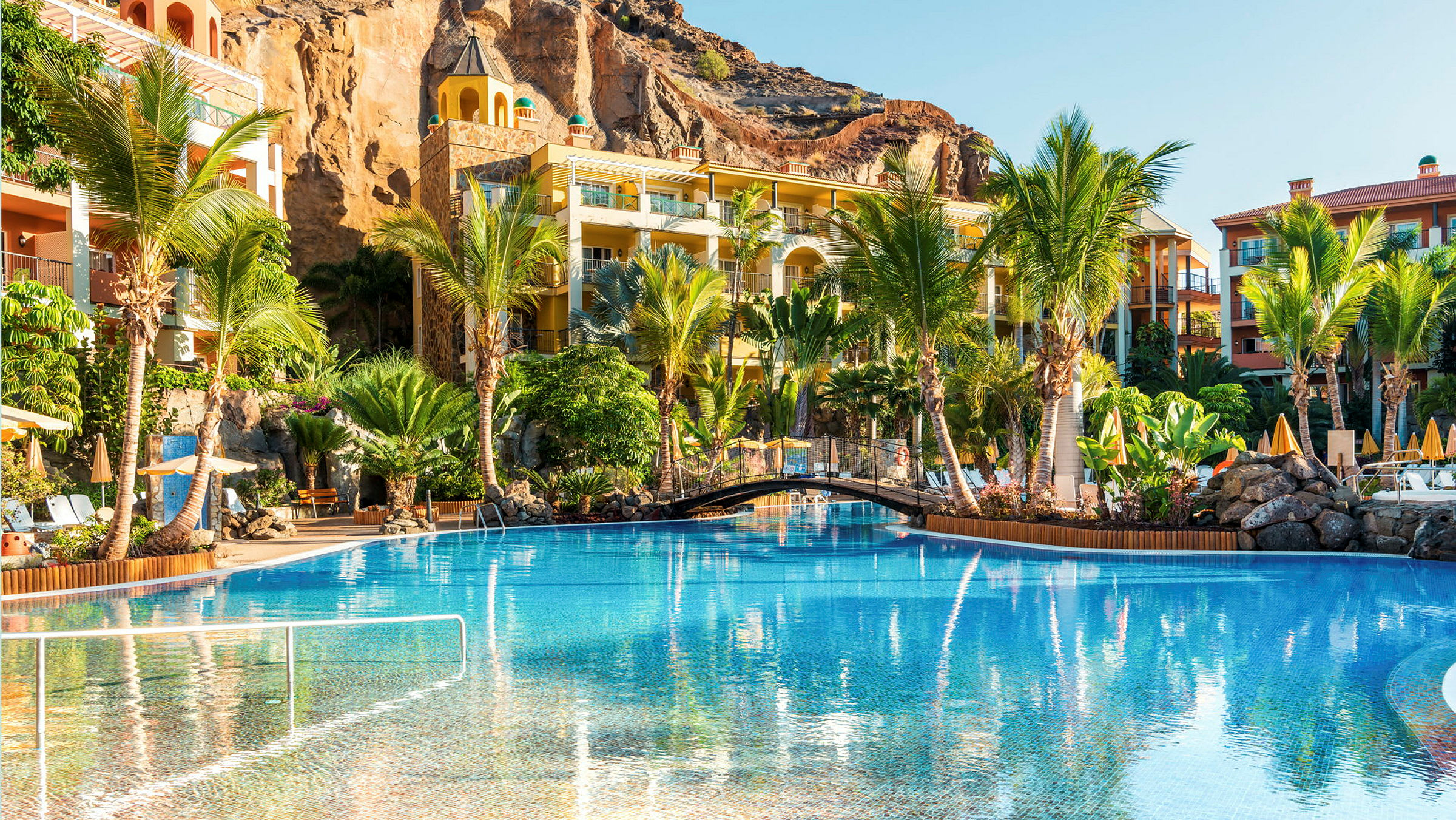 Hotellområde med pool, palmer och byggnader. (AI-genererad text)