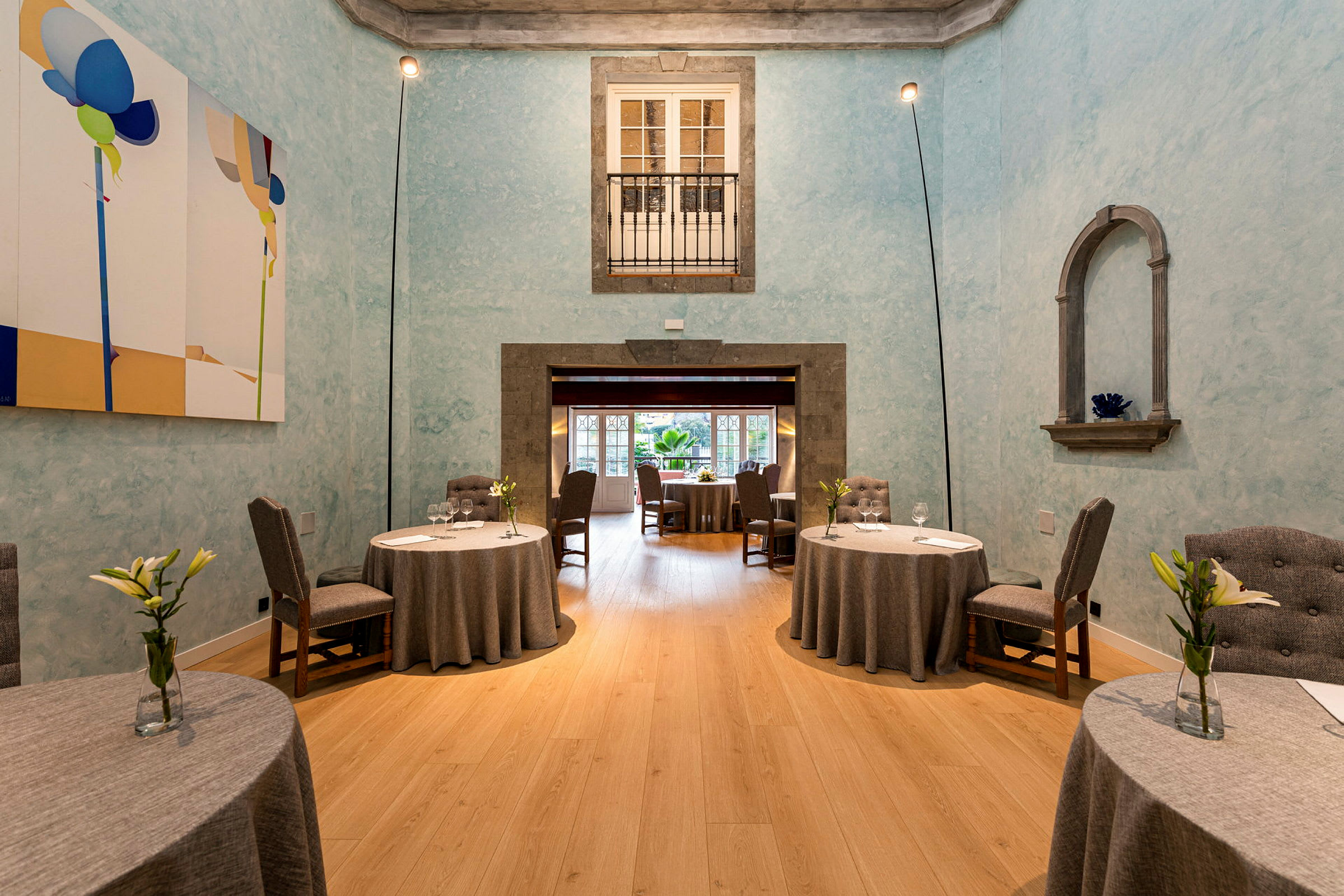 Ett rum inrett som en restaurang med runda bord, stolar och blå väggar. (AI-genererad text)