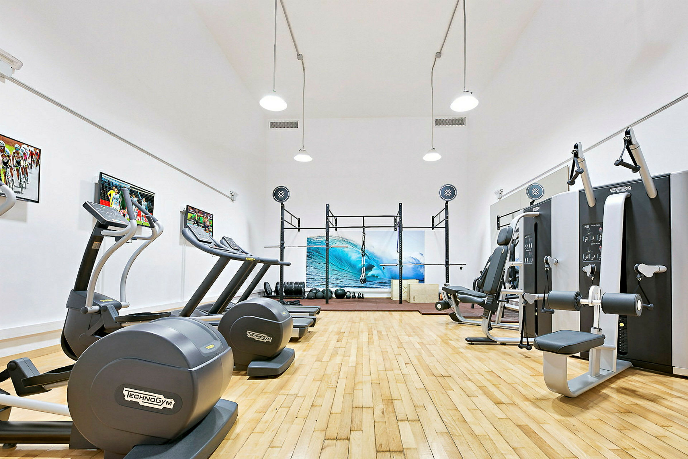 Ett gym med träningsutrustning och en bild på en surfvåg på väggen. (AI-genererad text)
