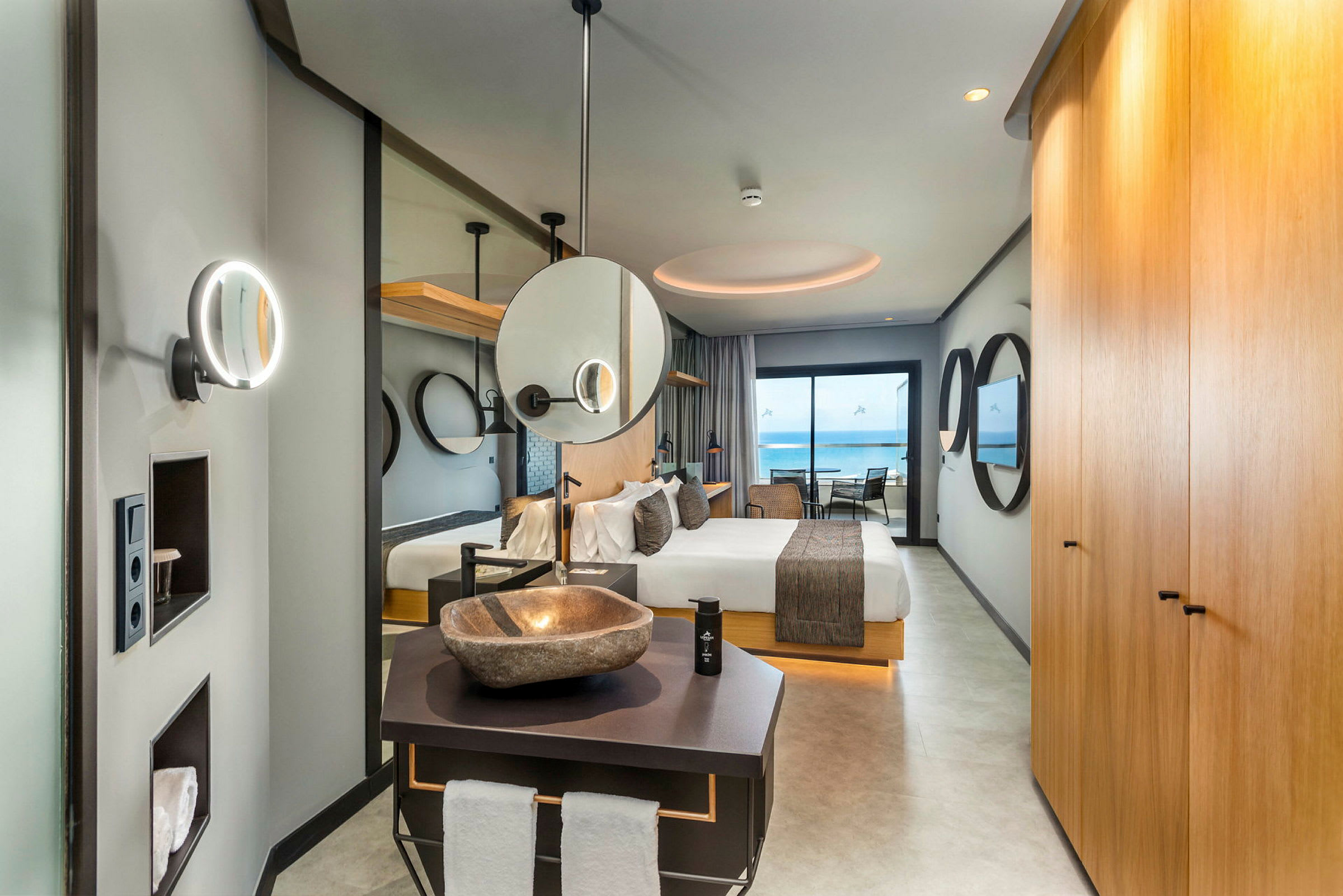 Interiör av ett elegant hotellrum med säng, badrum och utsikt mot havet. (AI-genererad text)