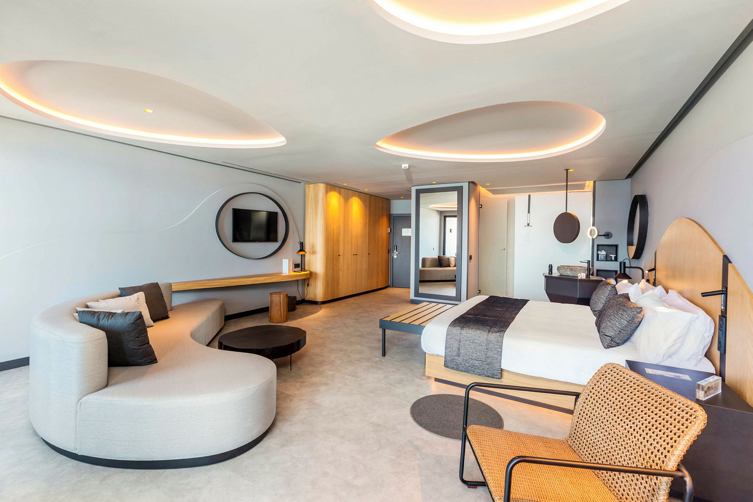 Ett modernt hotellrum med en säng, en soffa och en tegelmönstrad stol. (AI-genererad text)