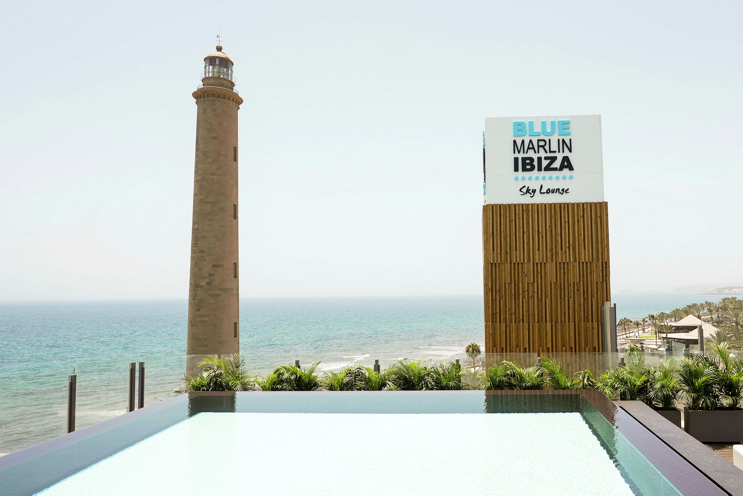 En fyr vid havet bredvid ett skylt som säger 'Blue Marlin Ibiza Sky Lounge'. (AI-genererad text)