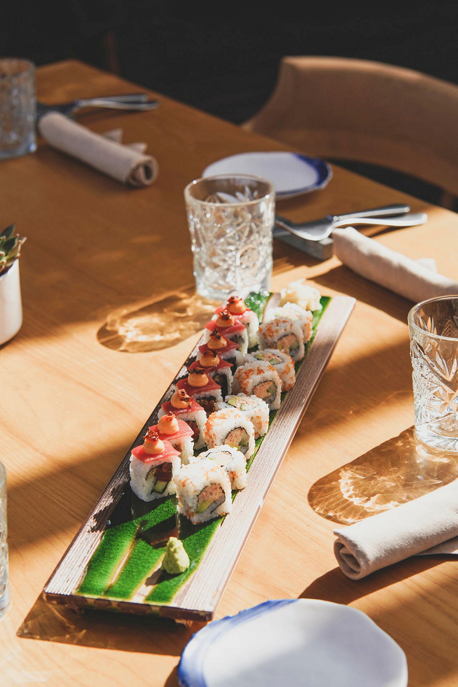 Sushi upplagd på ett långsmalt fat på ett bort dukat för måltid. (AI-genererad text)