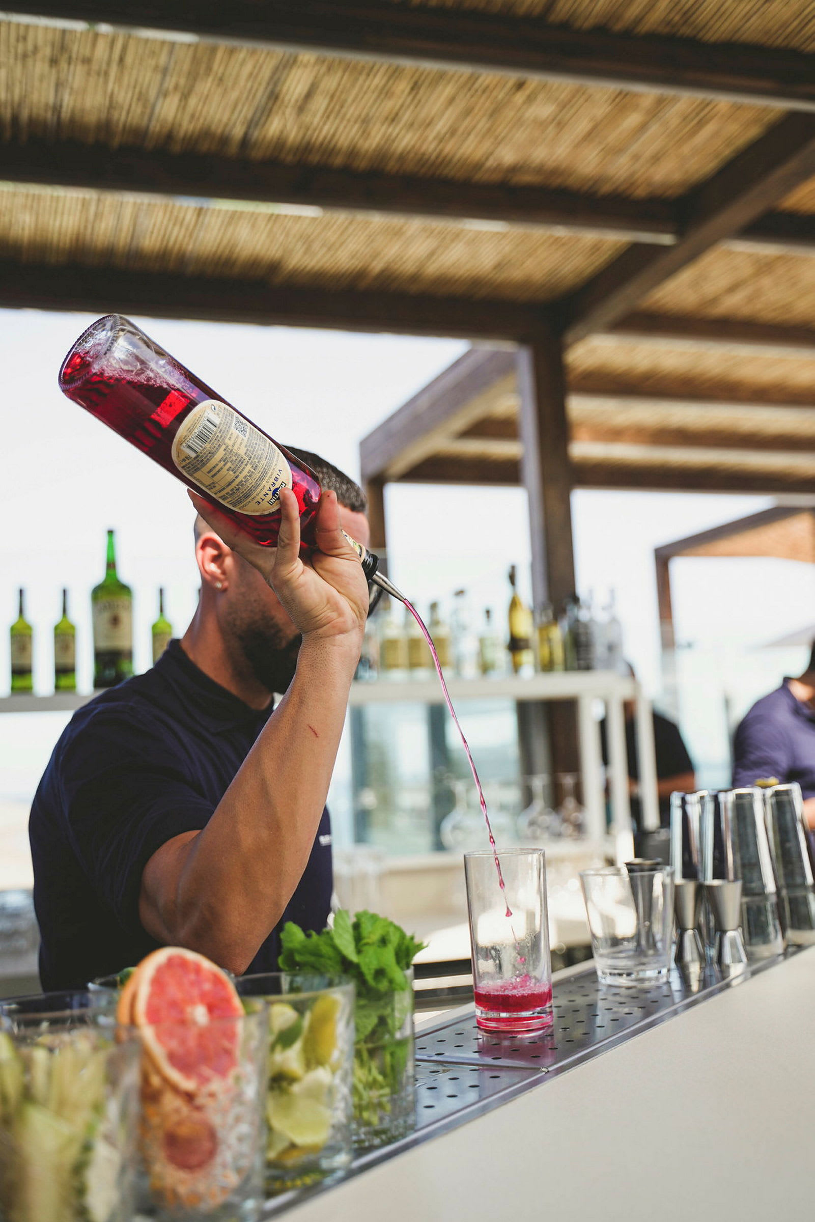 Bild på en bartender som häller upp rosa vätska i ett glas. (AI-genererad text)